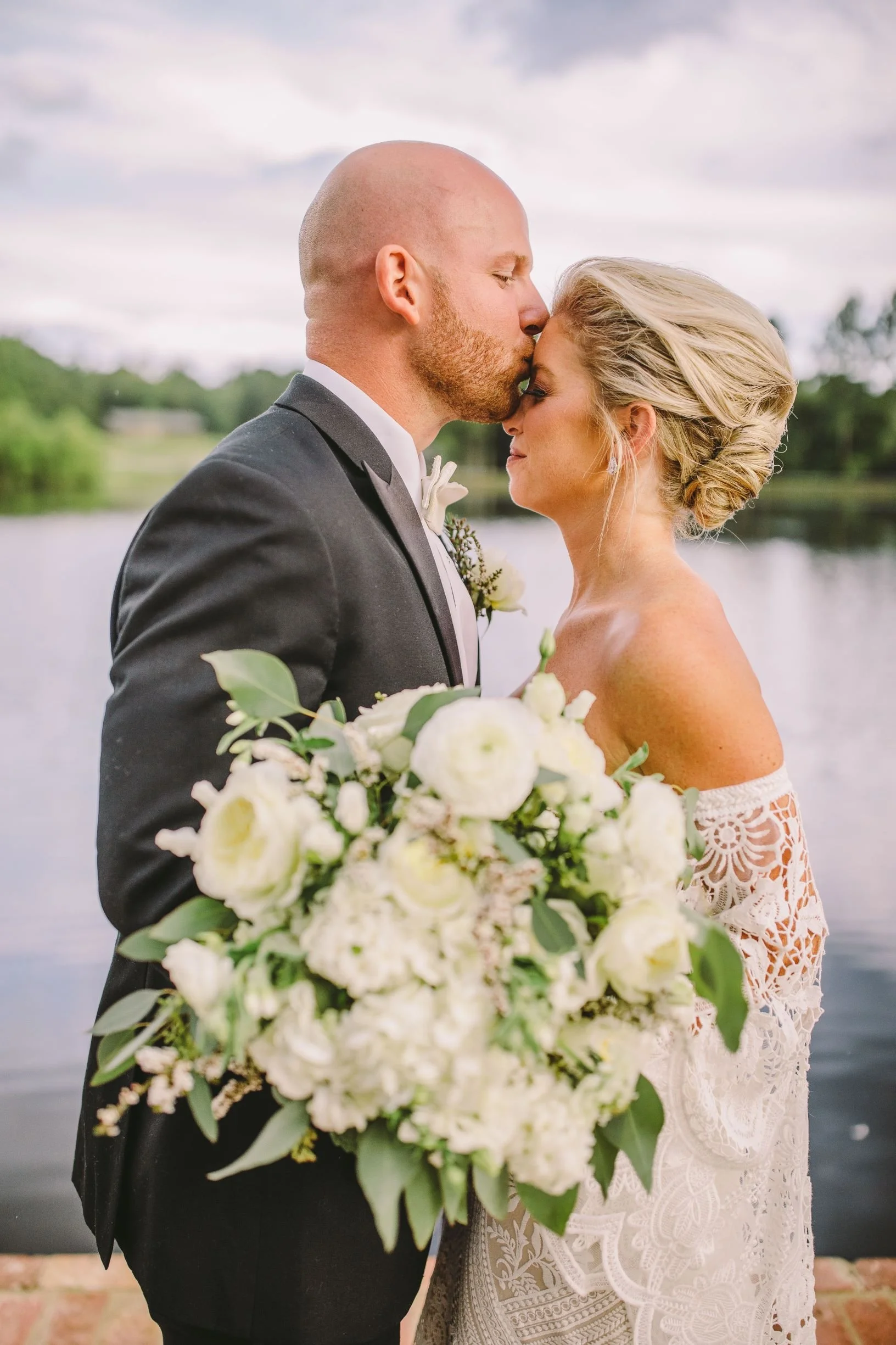 couple kissing along lakefront walkway after wedding ceremony at the jefferson oxford