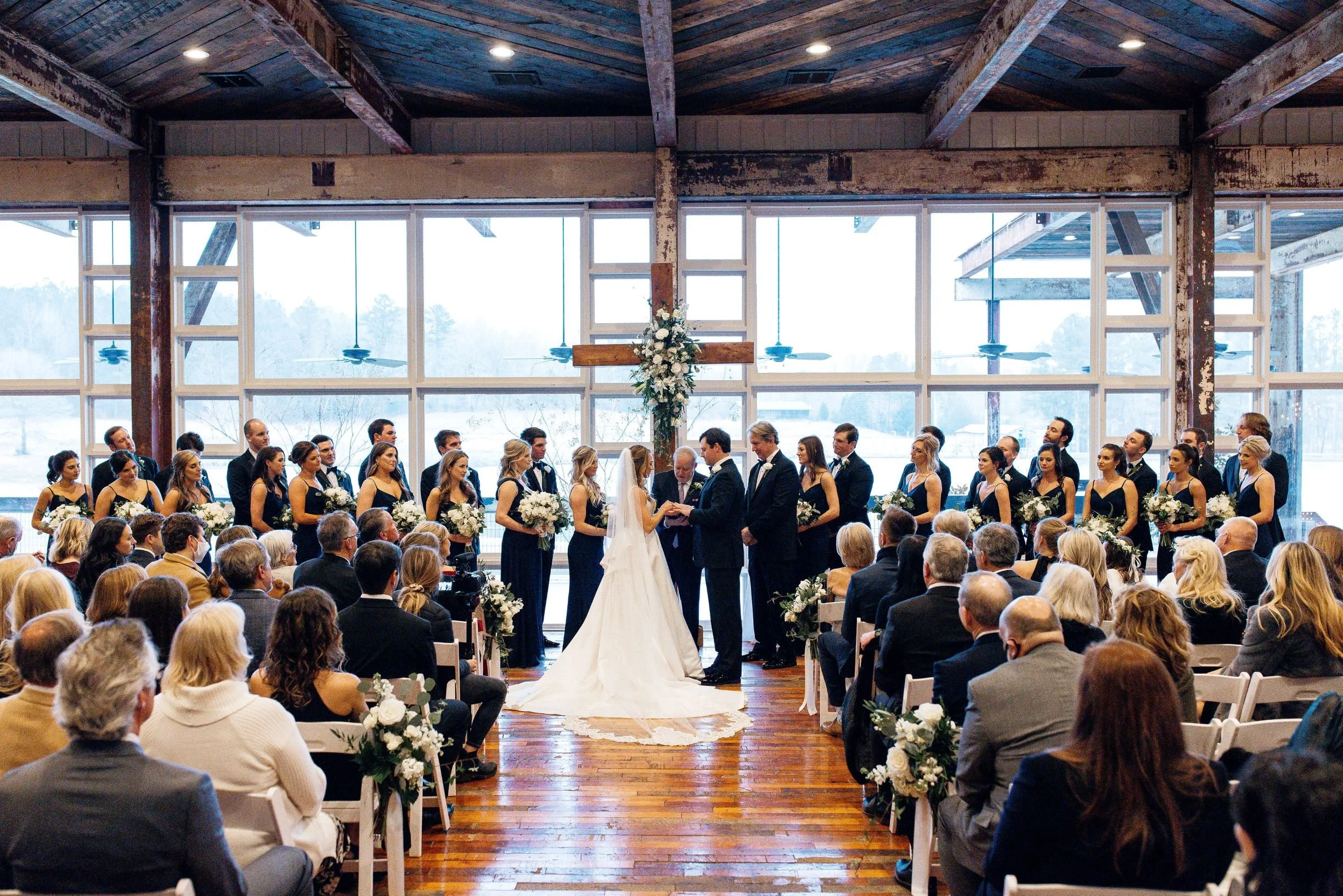 bride & groom during a wedding ceremony in front of wall of windows in lakeside room at Jefferson oxford