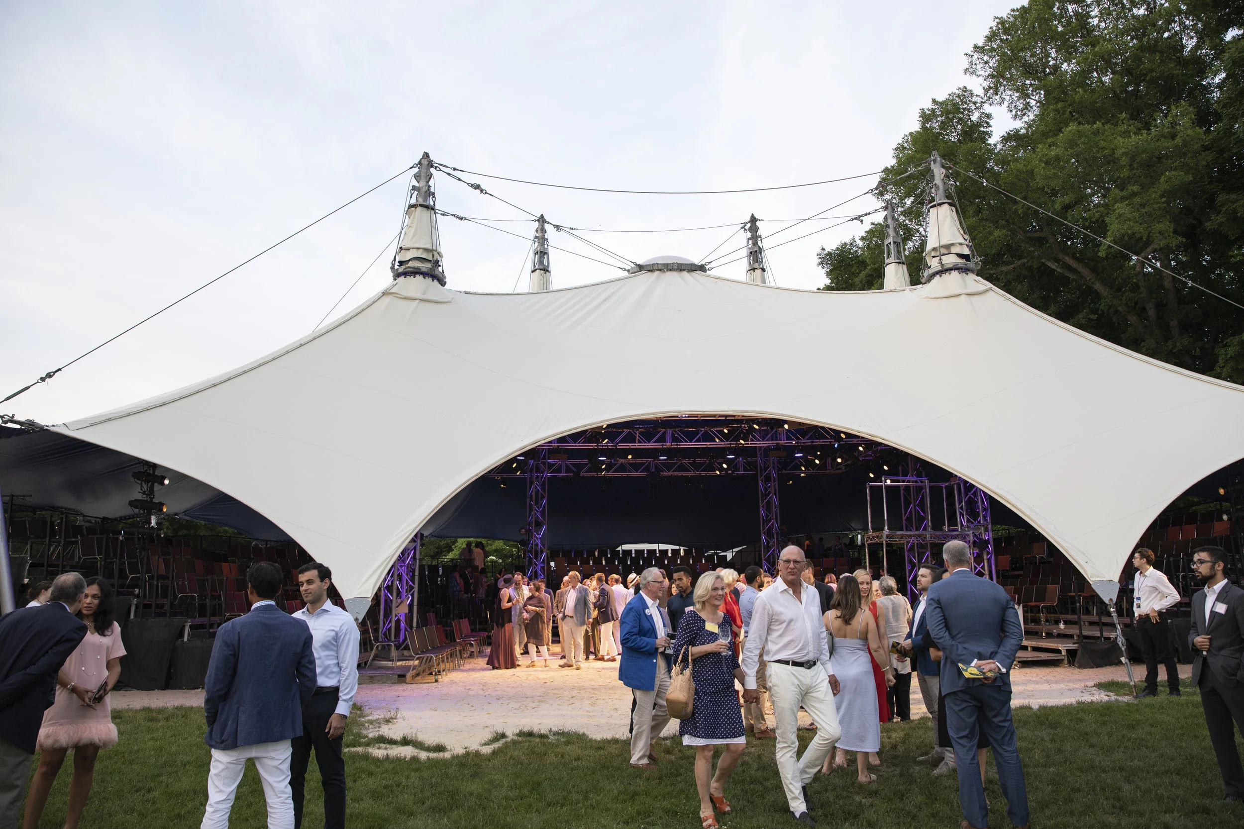 Guests gathering outside an illuminated white event tent at a Food in Motion gala reception.