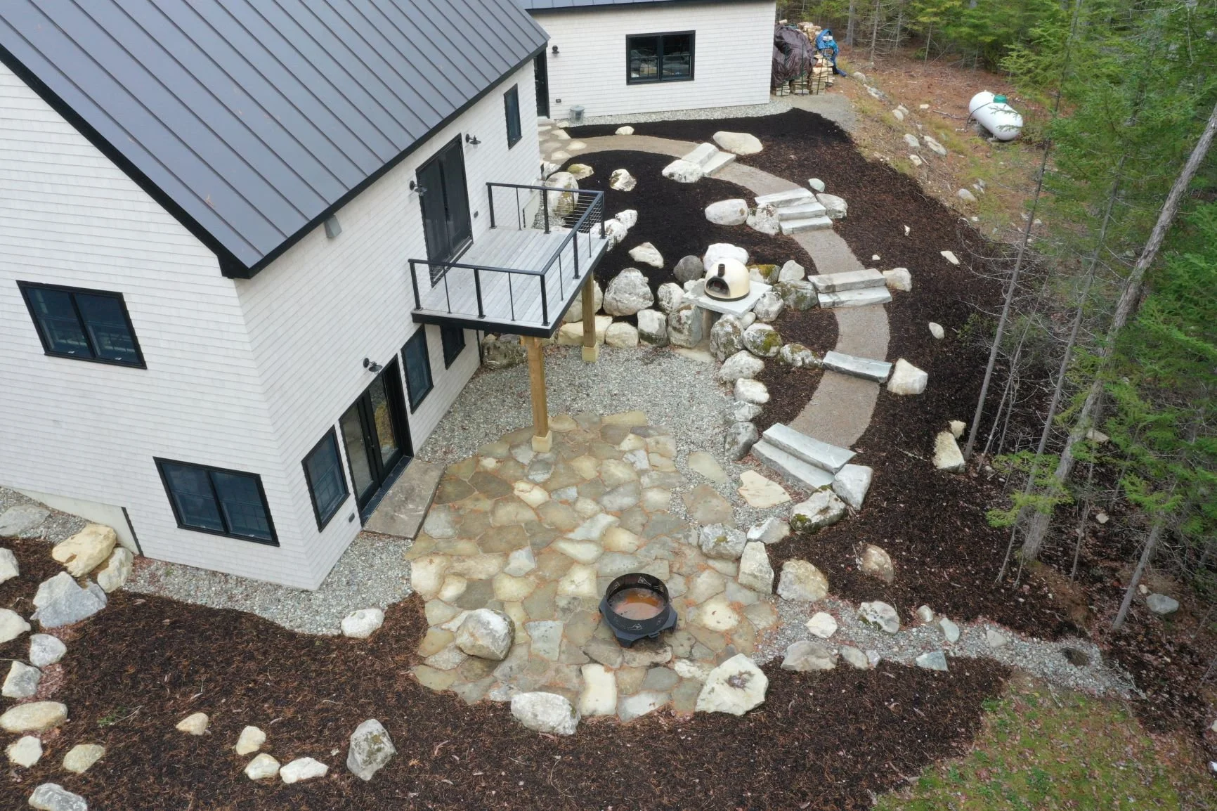 Aerial view of lower stone patio, stone steps, boulders & pizza oven