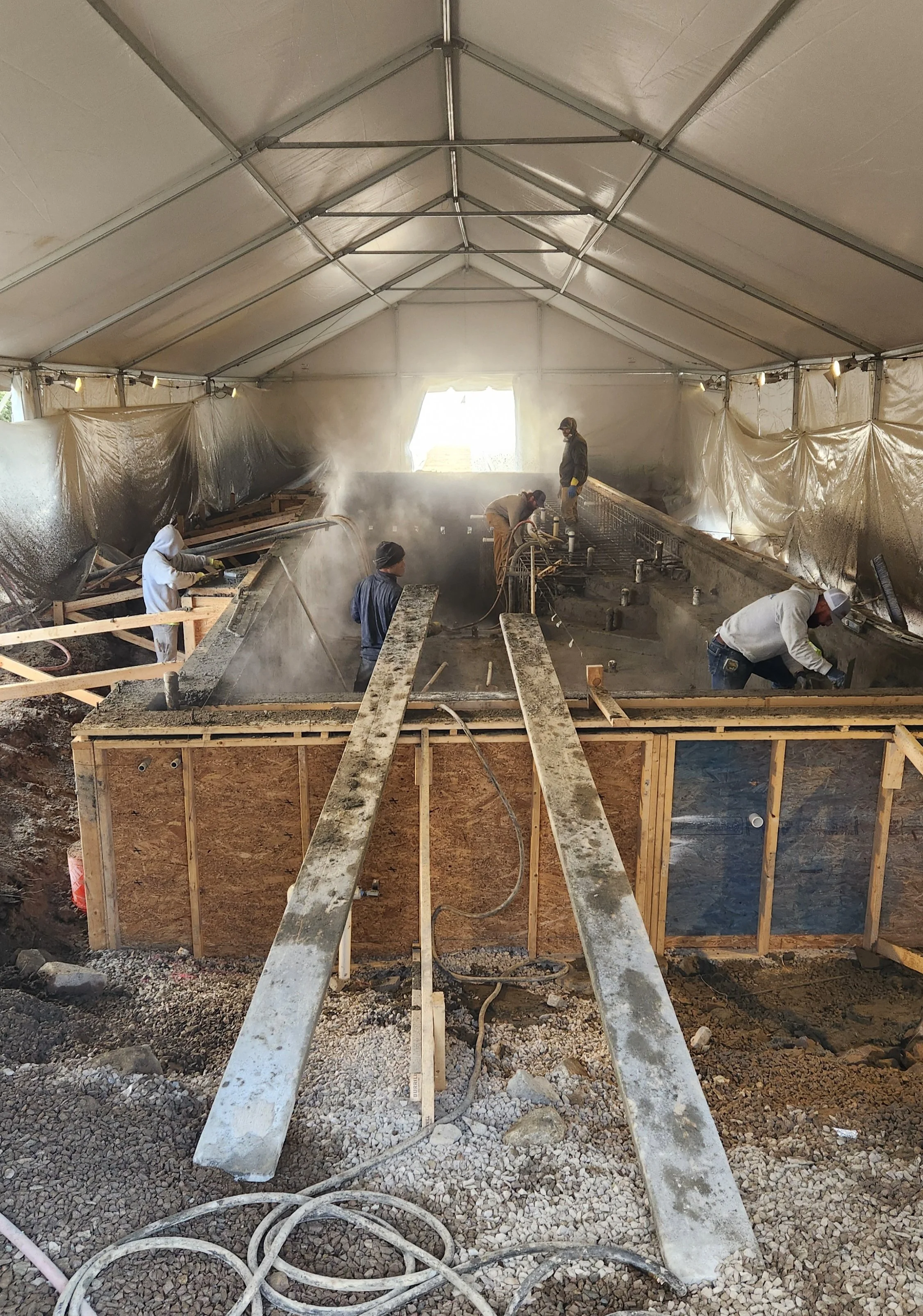 Spraying on the gunite shell for the pool under a tent