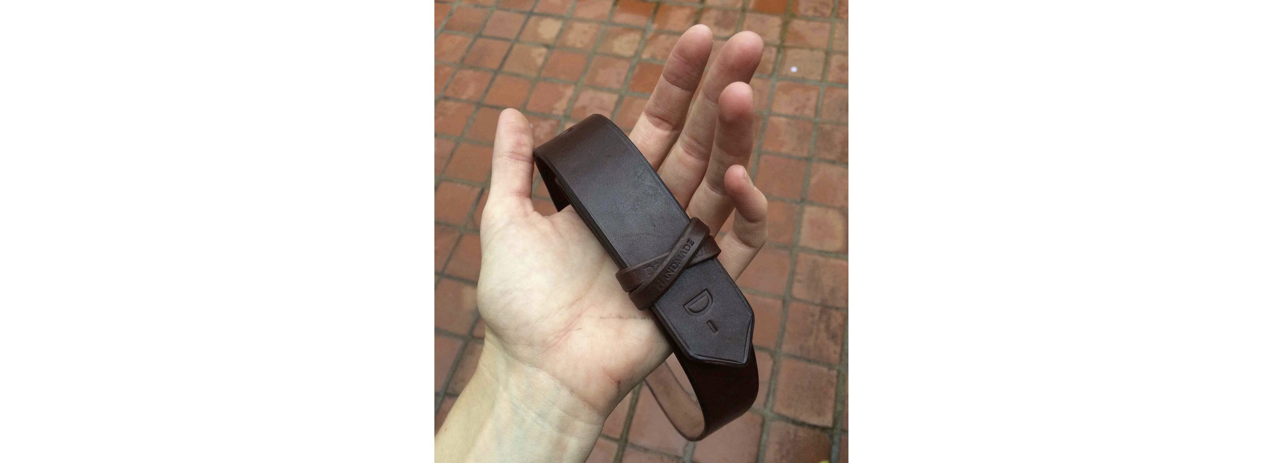 A Men's Mahogany belt strap embossed with the signature 'D-'.
