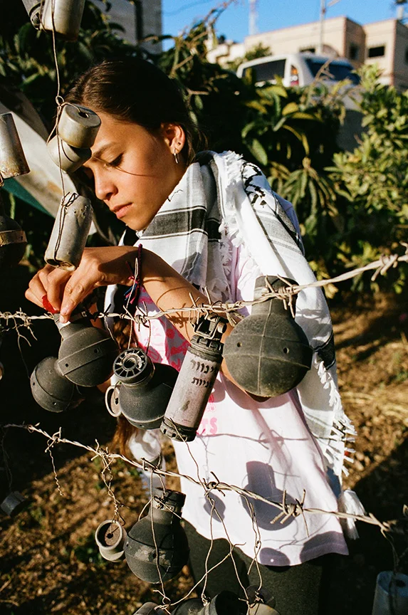 Janna Ayyad placing a flower she picked from her yard into an empty teargas canister that was shot at her home in Nabi Saleh by Israeli forces. Over the several years she has collected these canisters from around the house and yard to put on display as a way to show her families resistance to the occupation. 