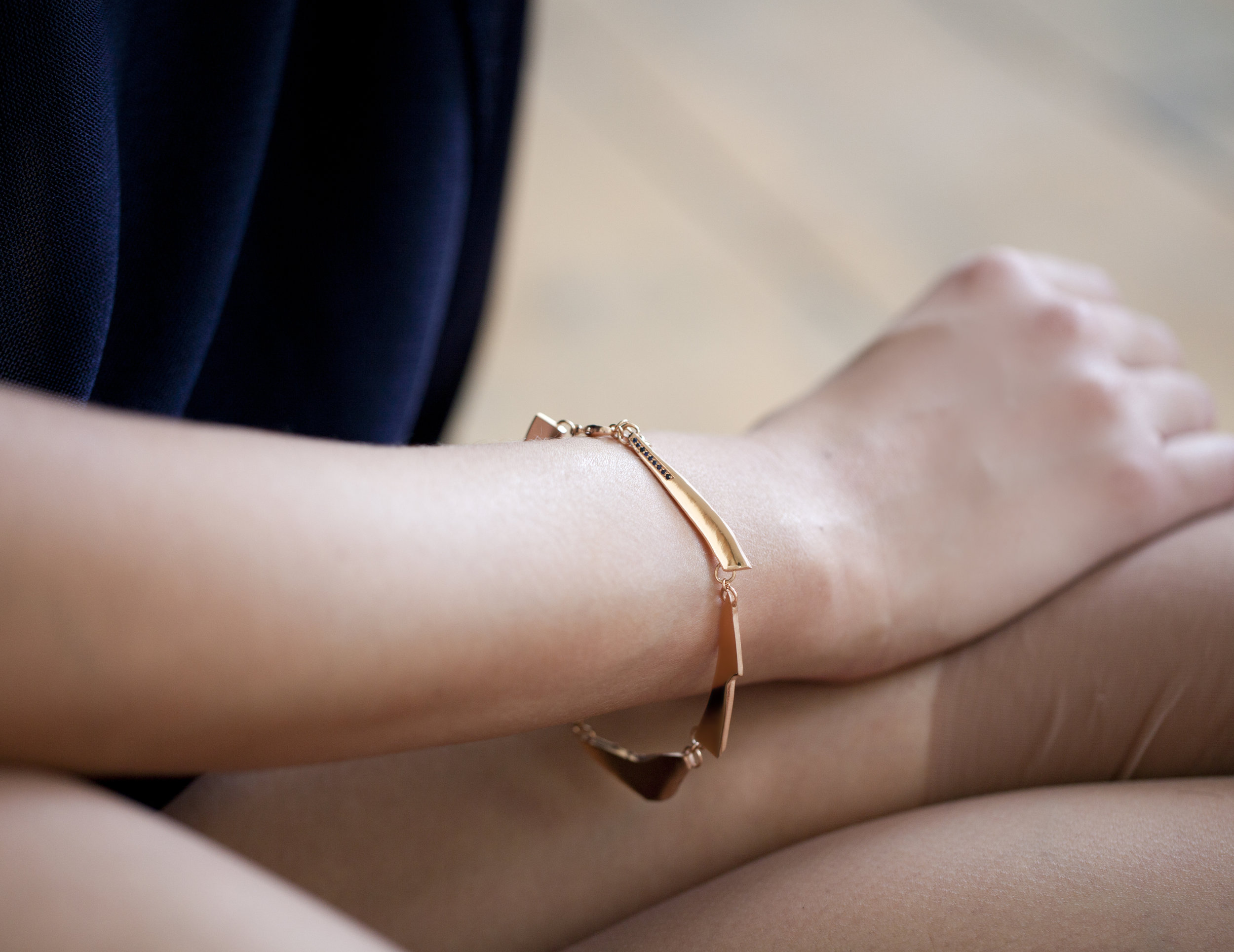 Abi Penhale wearing Asymmetric Bracelet in rosé gold plated recycled sterling silver with sapphires from GINA MELOSI's //SHATTEREDfragments// collection
