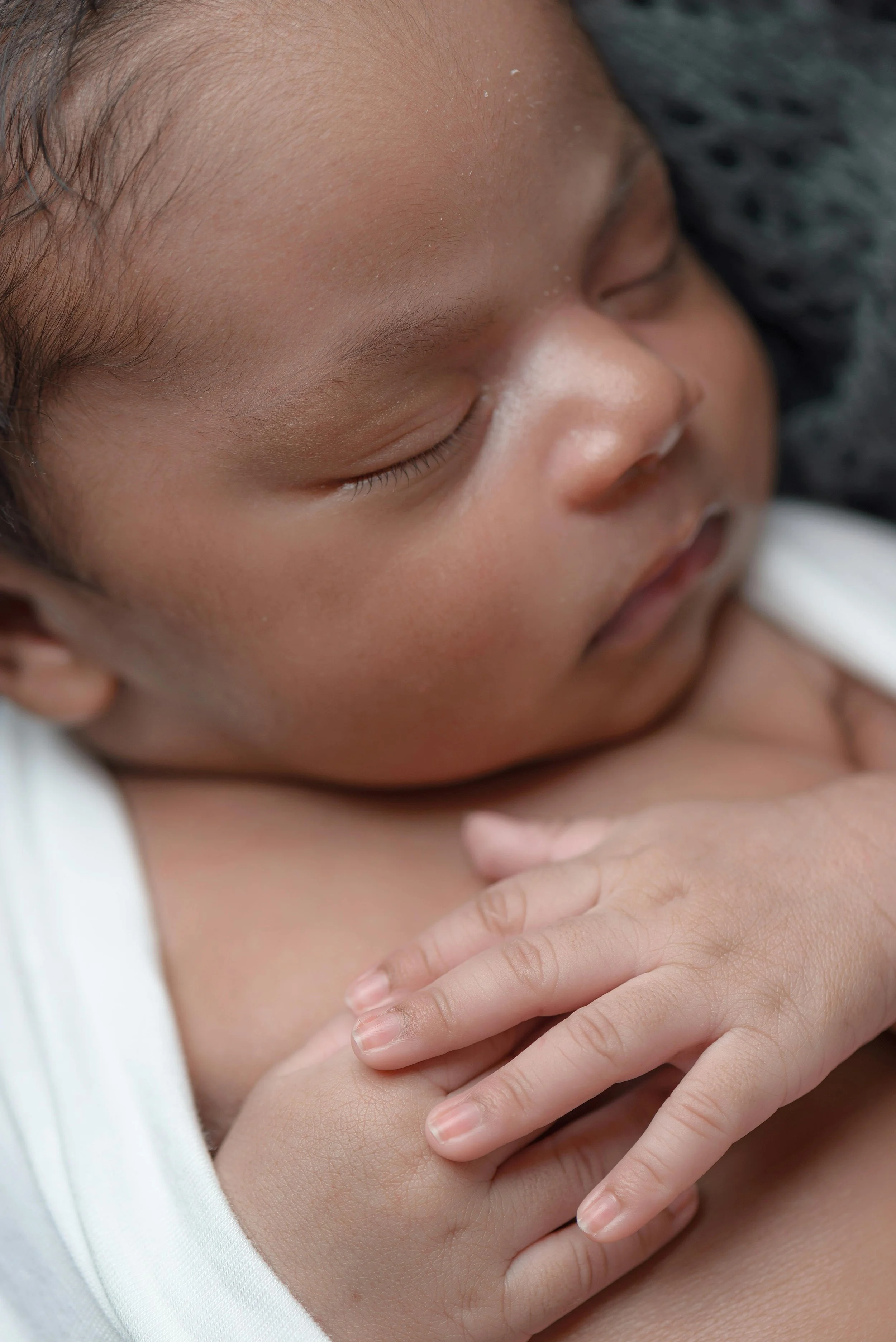 Sleeping baby, hands clasped. Beside information on how Toronto Ostepathy can help with infant tension and feeding.