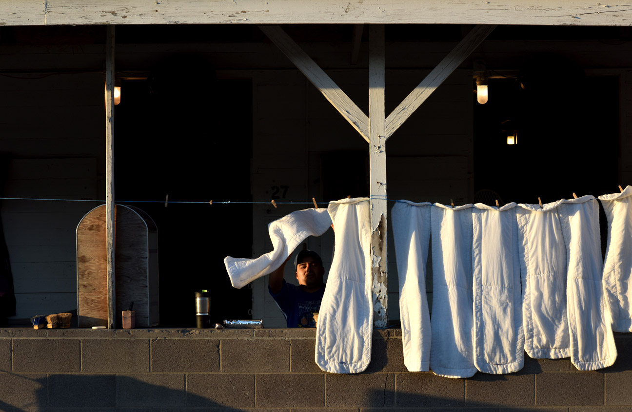 Groom Sol Melchor hangs leg wraps at Churchill Downs. Grooms work for thoroughbred trainers and are responsible for day-today care of horses. Melchior has worked at Churchill Downs for 10 years and says, "It's just a job." 