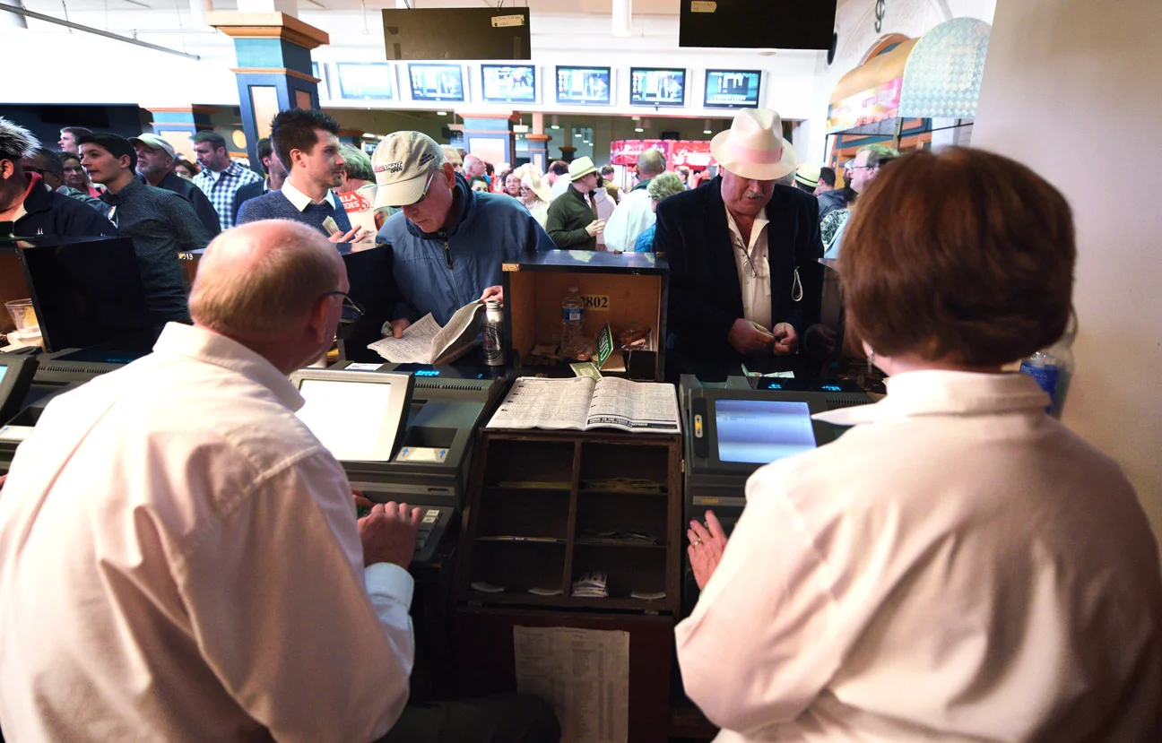 Teller Terry Smith, right, takes a bet at a betting window on the Thursday before Derby Day. An estimated $12 million was bet on last year's Kentucky Derby at Churchill Downs, and millions more are wagered off site.