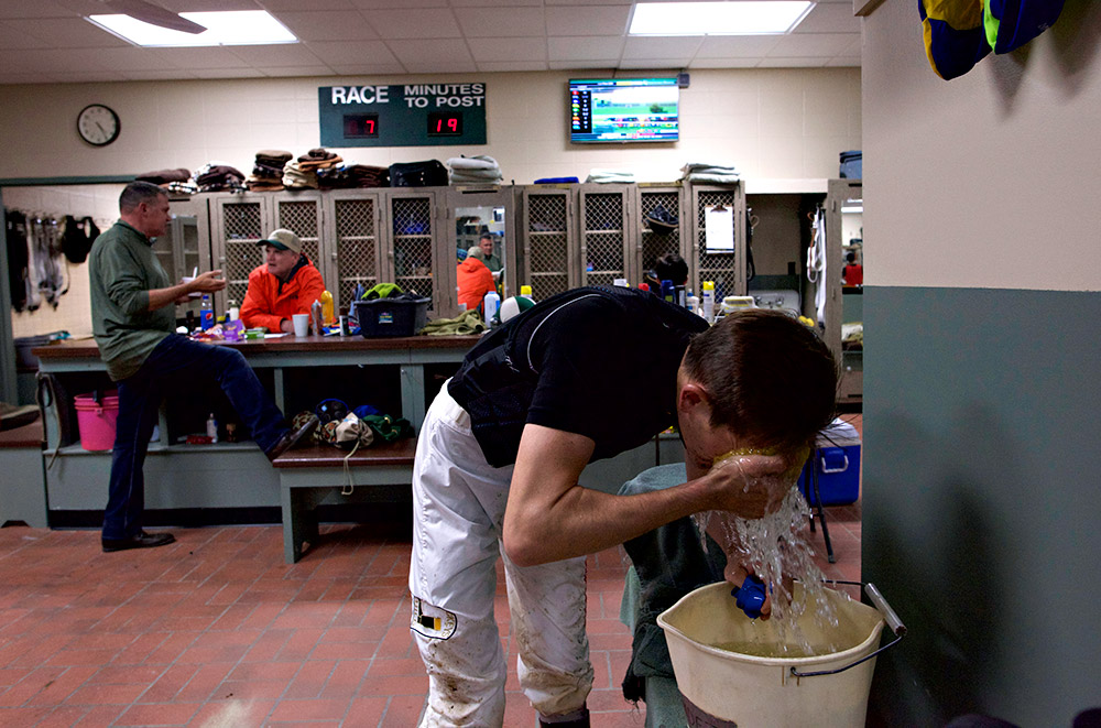 Between races, Hernandez washes his face in the jockey room at Churchill Downs on Thursday. Each jockey has his own makeshift shower bucket for cleaning mud off his face.