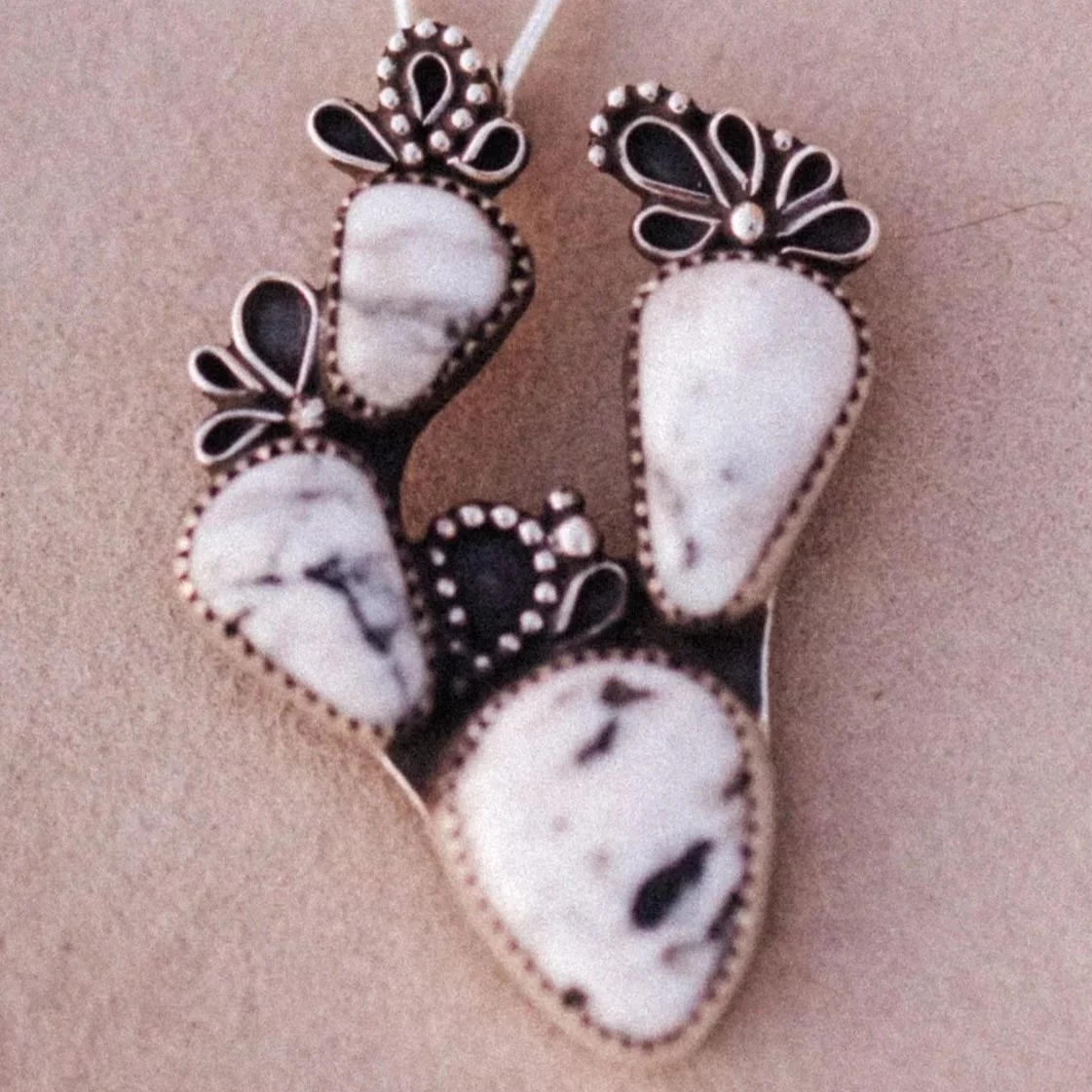 A sterling silver pendant with white and black white buffalo stones with beaded and wire detailing.