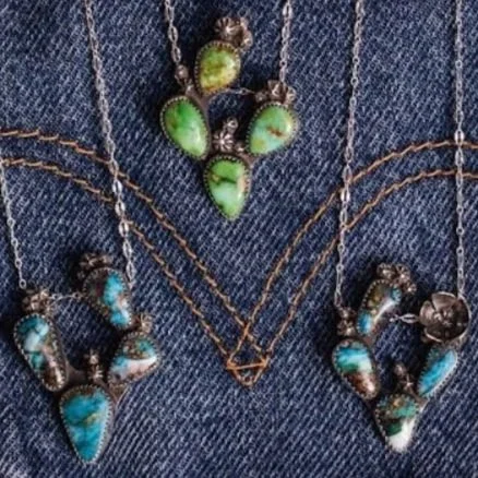 Cactus necklaces with green and blue stones on denim fabric.