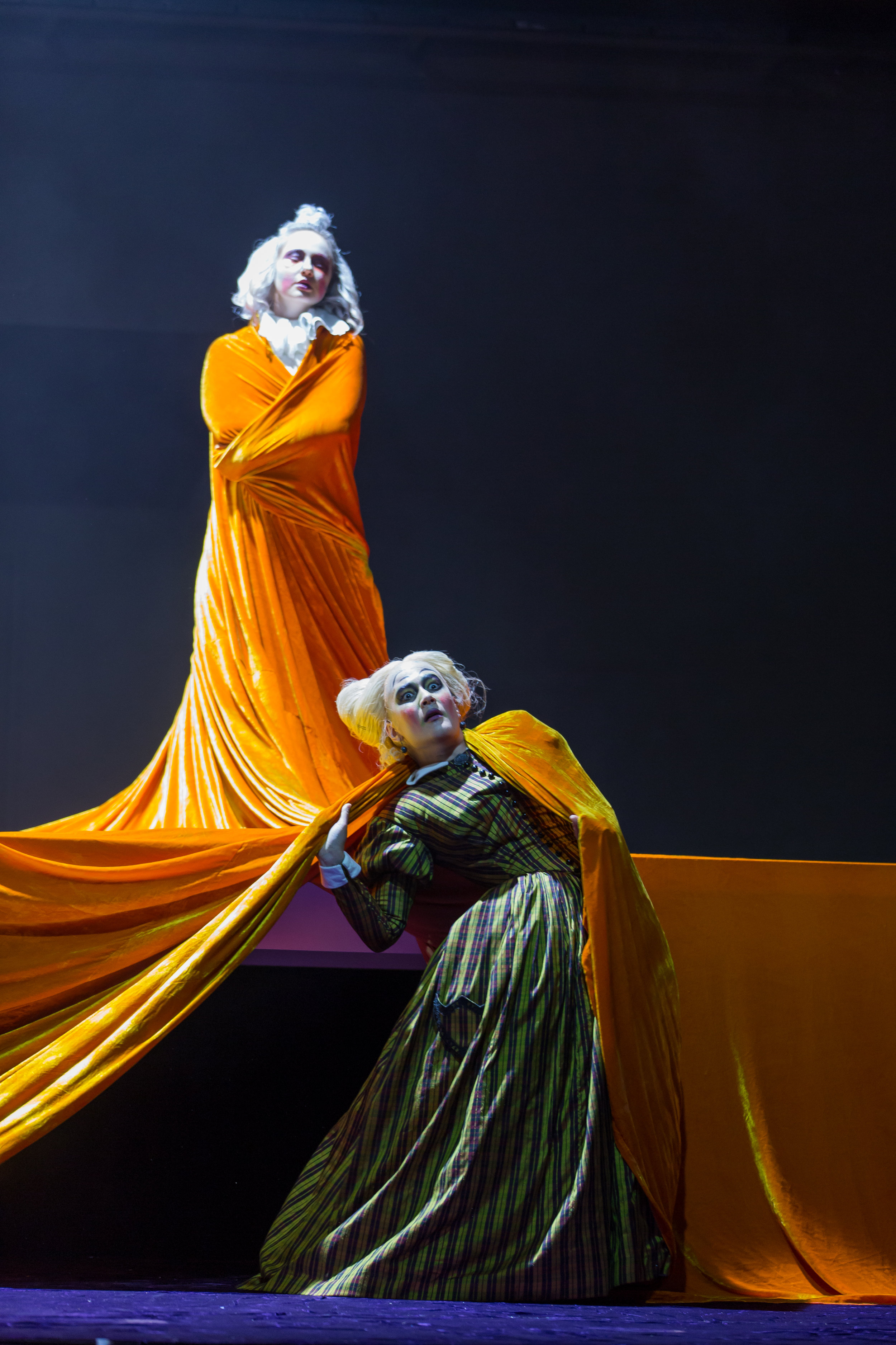 From The Juniper Tree : Megan Mikailovna Samarin, the son, drapped by the golden tablecloth, stands triumphantly over Annie Rosen, the stepmother; photo by Scott Suchman and courtesy of Wolf Trap Opera.