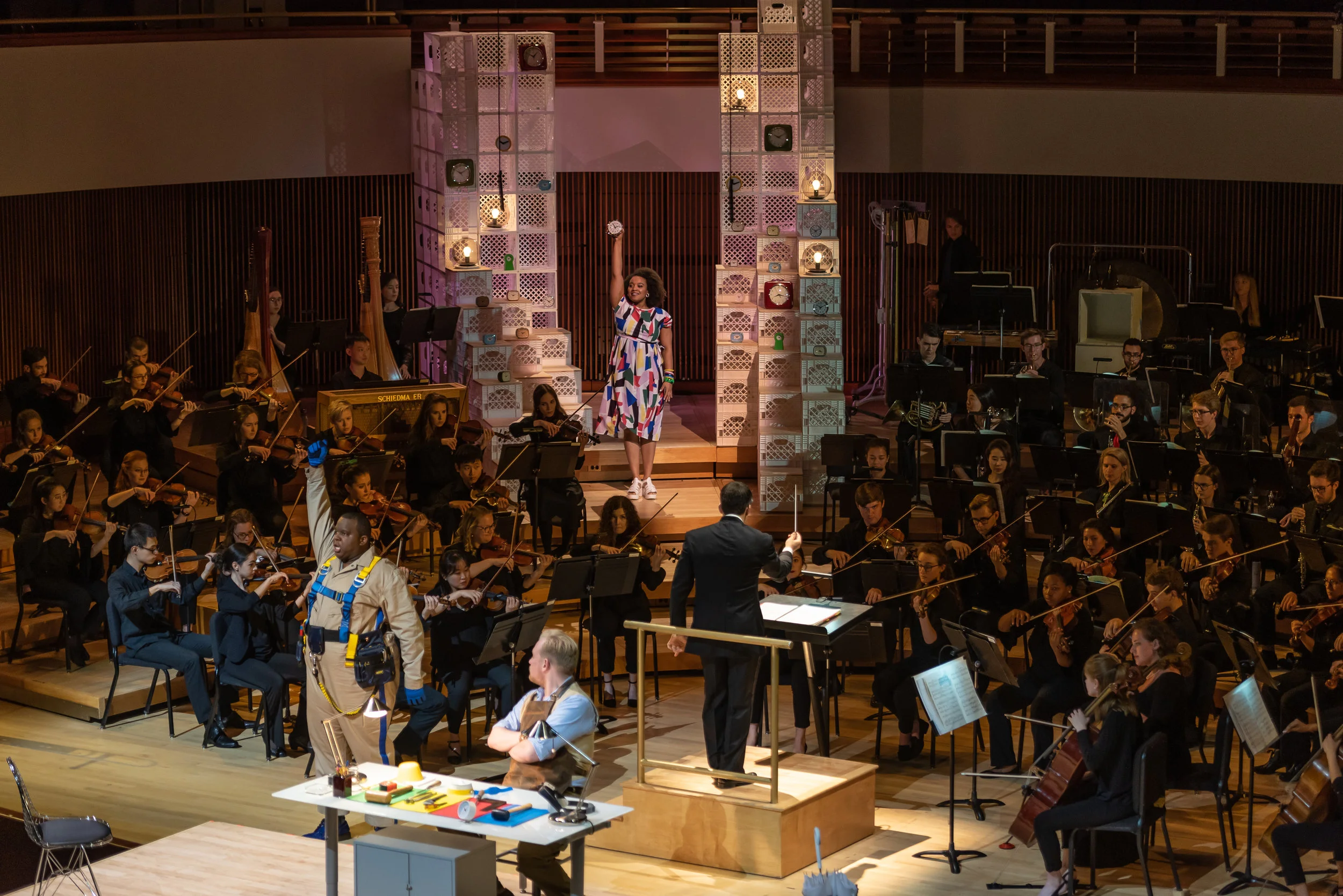Joshua Conyers as Ramiro, the muleteer (standing), Ian Koziara as Torquemada, the clock maker (seated), and Taylor Raven as Concepcion, the clockmaker’s wife (lighted in back). Photo by Rob Wallace/MIndful Photo; courtesy of Wolf Trap Opera.