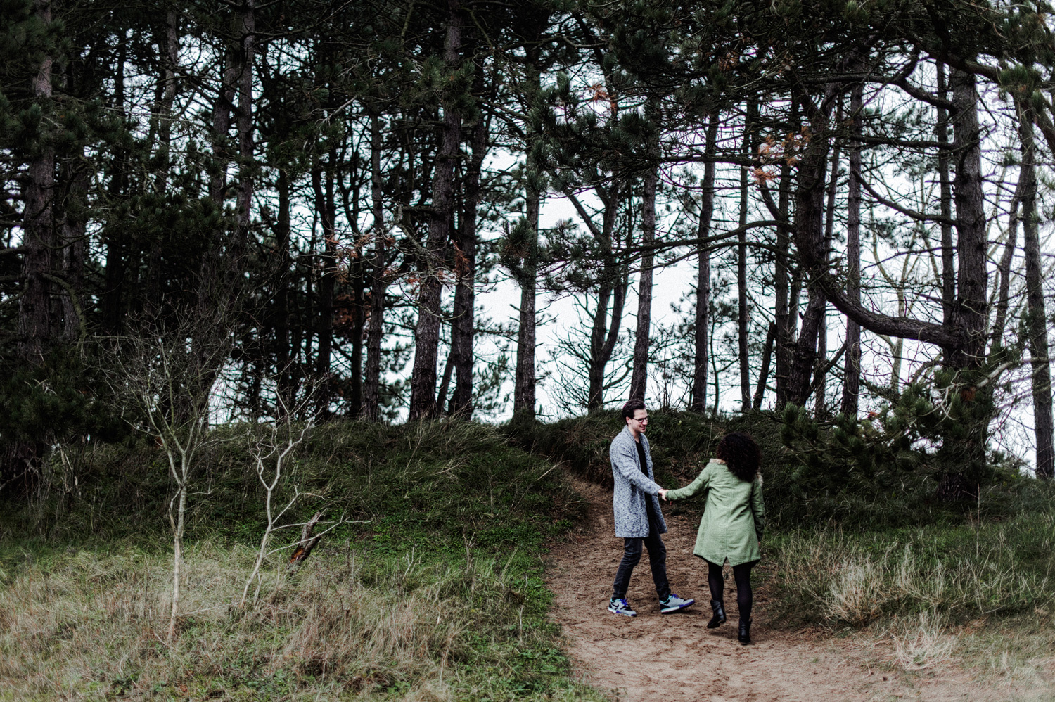 Couple holding hands and walking up dunes