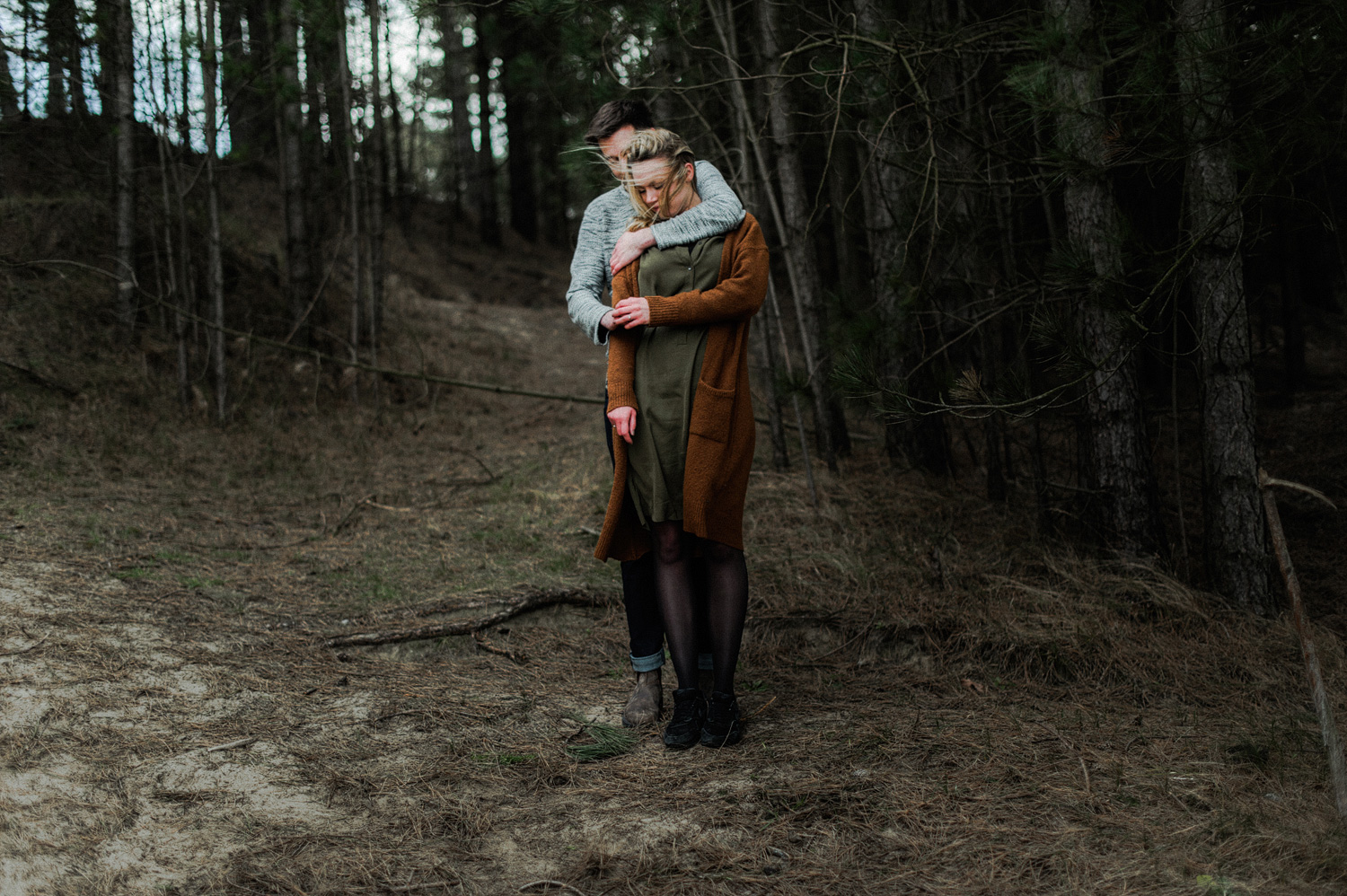 Couple standing behind each other in the woods