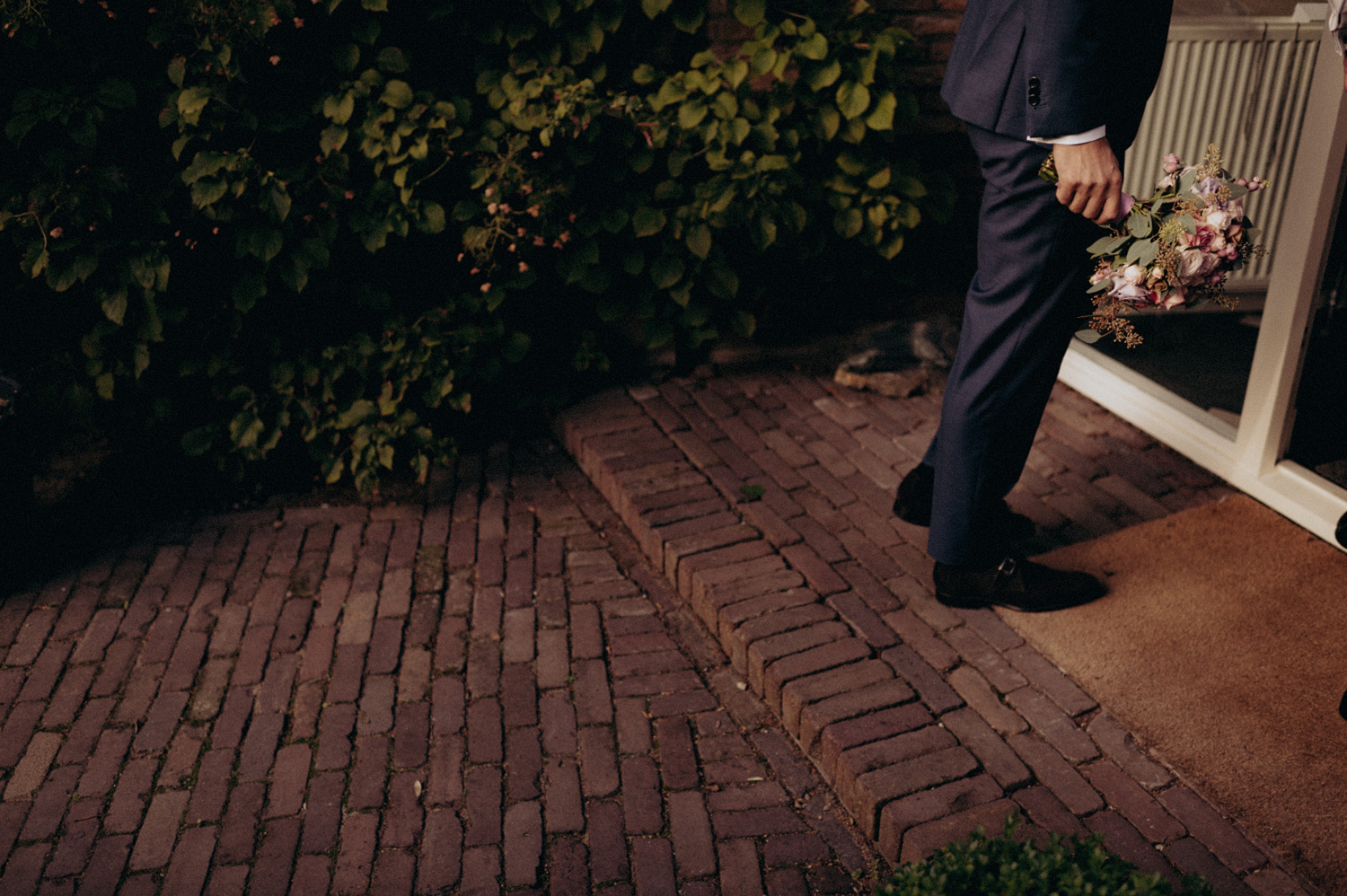Groom ringing doorbell with bouquet for bride