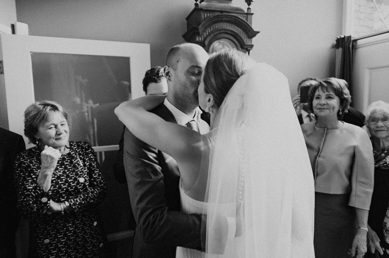 Groom kissing his bride surrounded by weddings guests