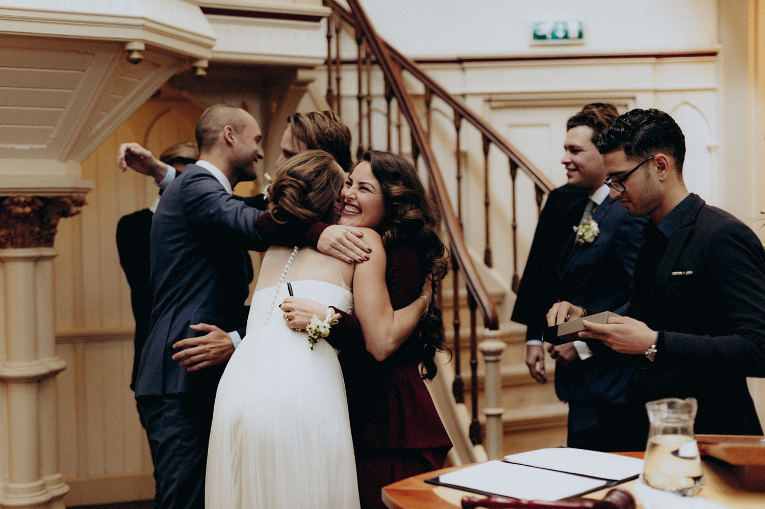 Friends of bride and groom hugging couple