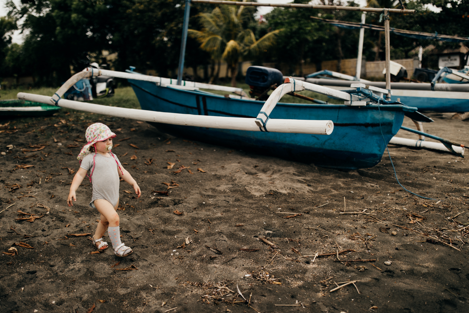 Kid walking next to boat on the beach in Bali, Indonesia