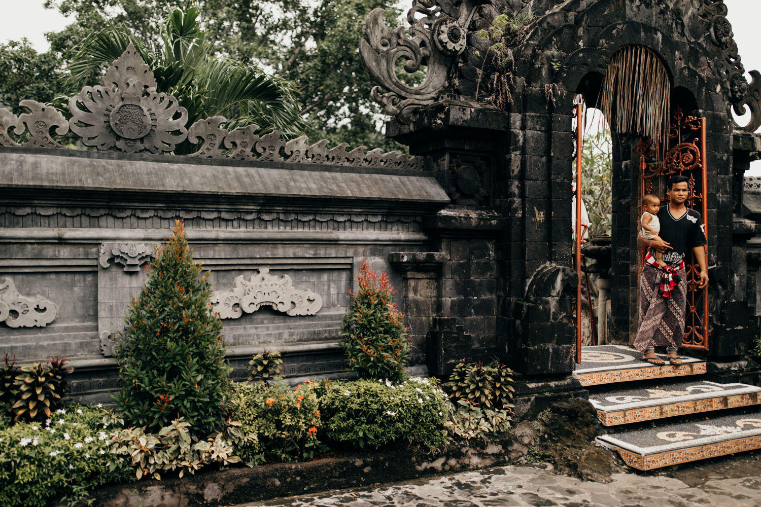 Father with kid on arm at temple entrance in Bali, Indonesia