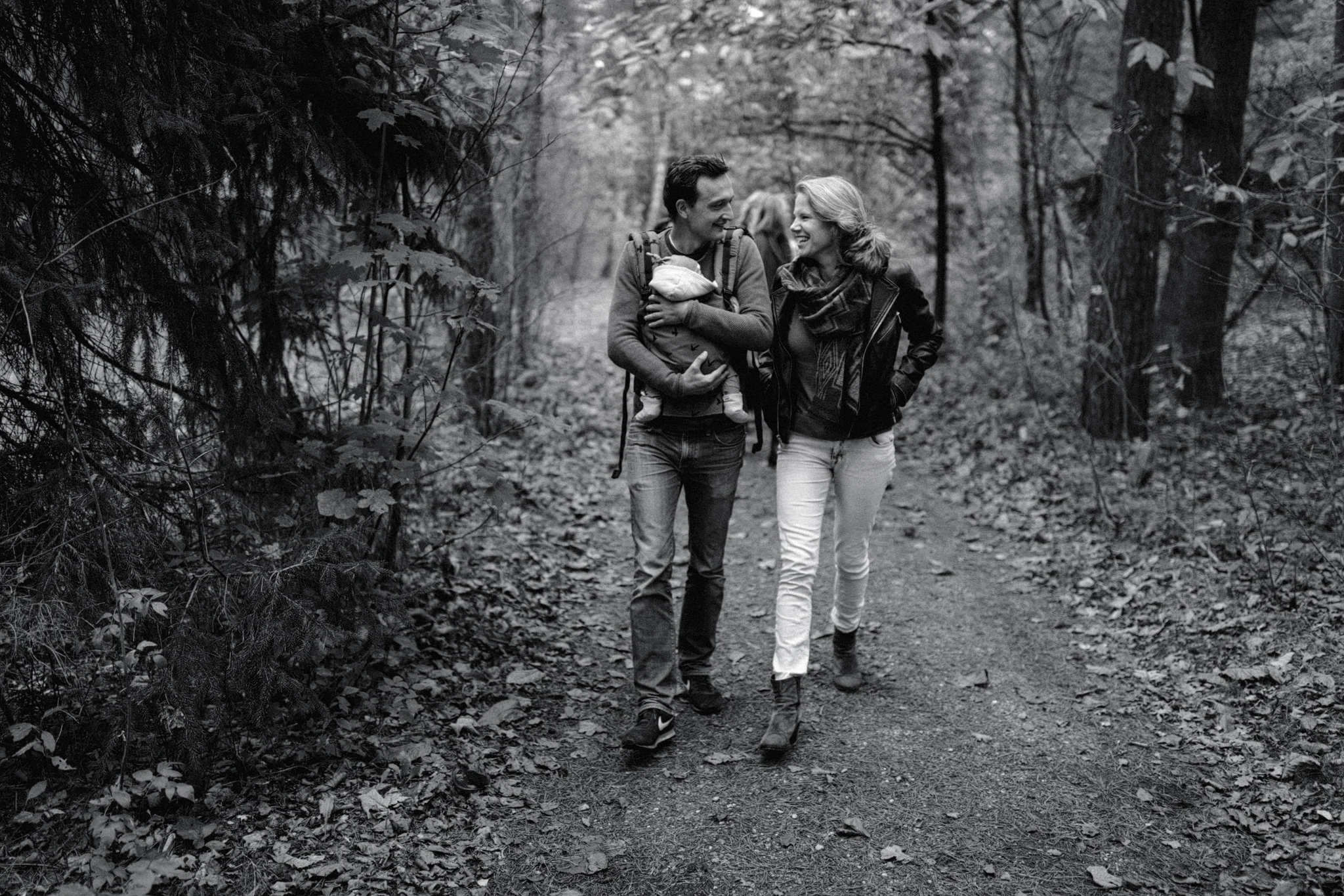 Mother and father walking laughing holding baby