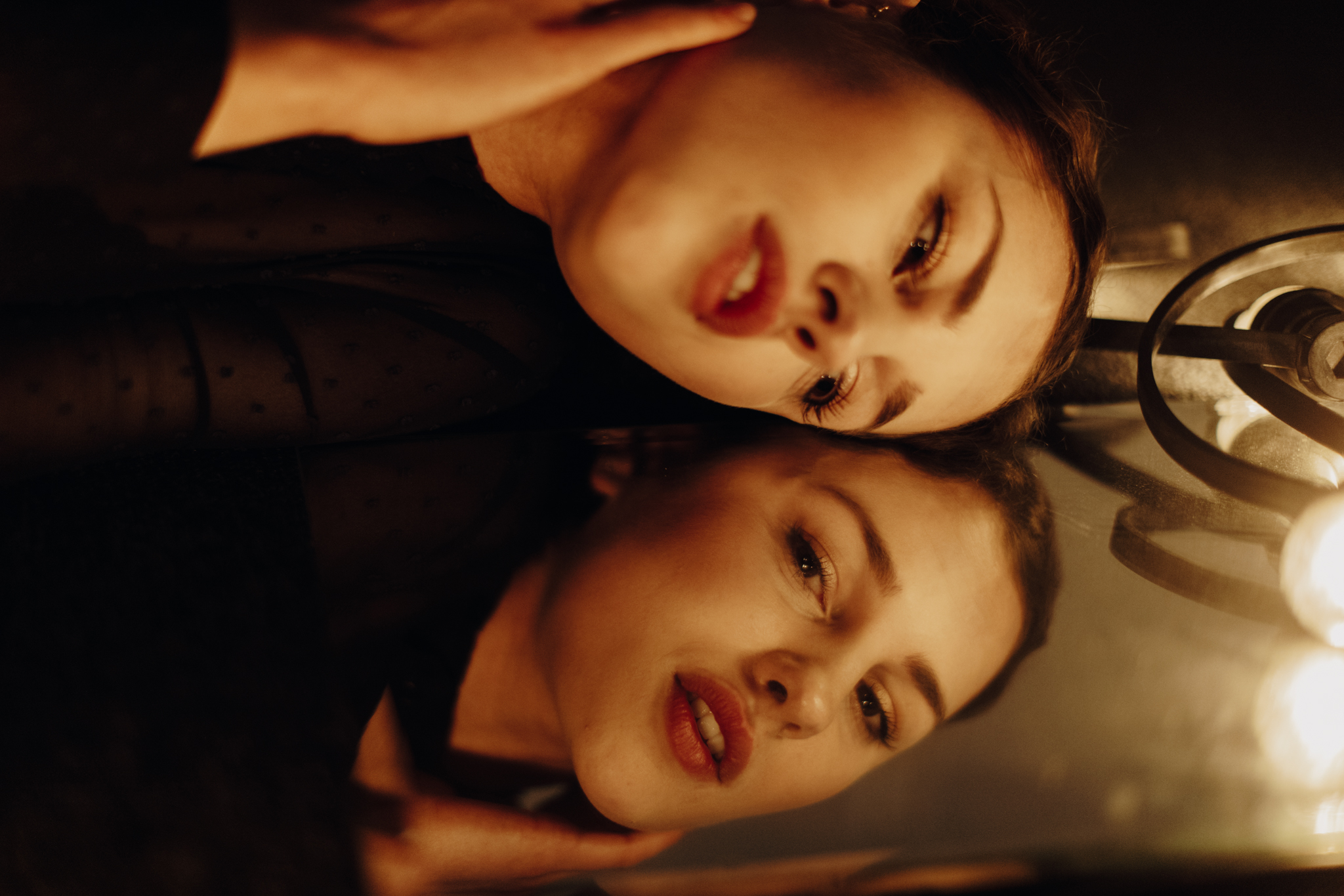 Girl lying on floor with face on mirror surrounded by string lights