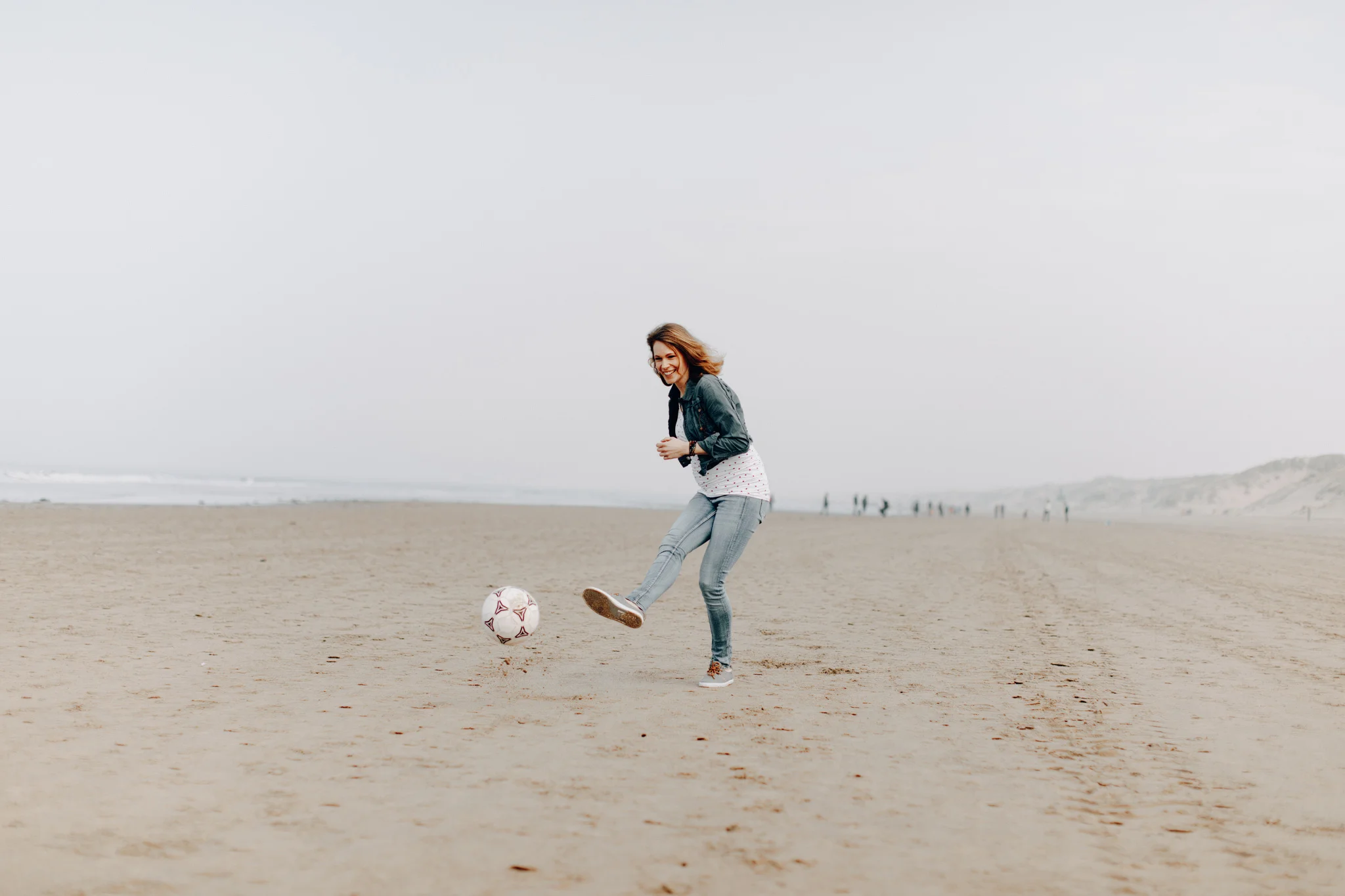 Pregnant woman playing soccer at the beach