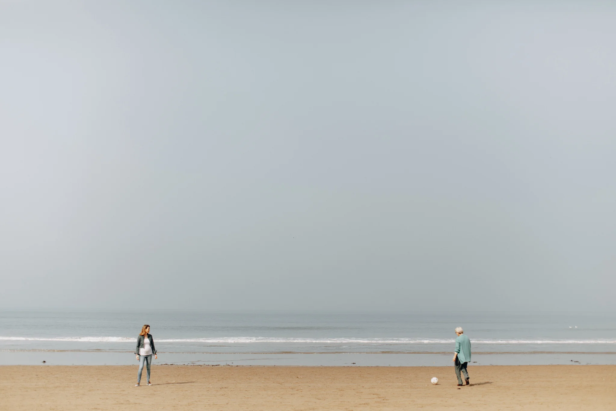 Beach shoreline with woman playing soccer