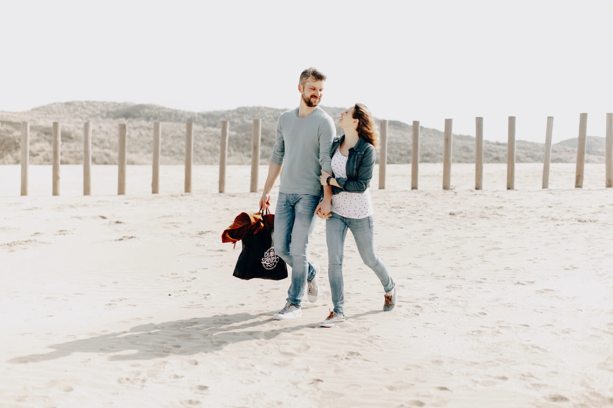 Couple walking at the beach smiling at each other