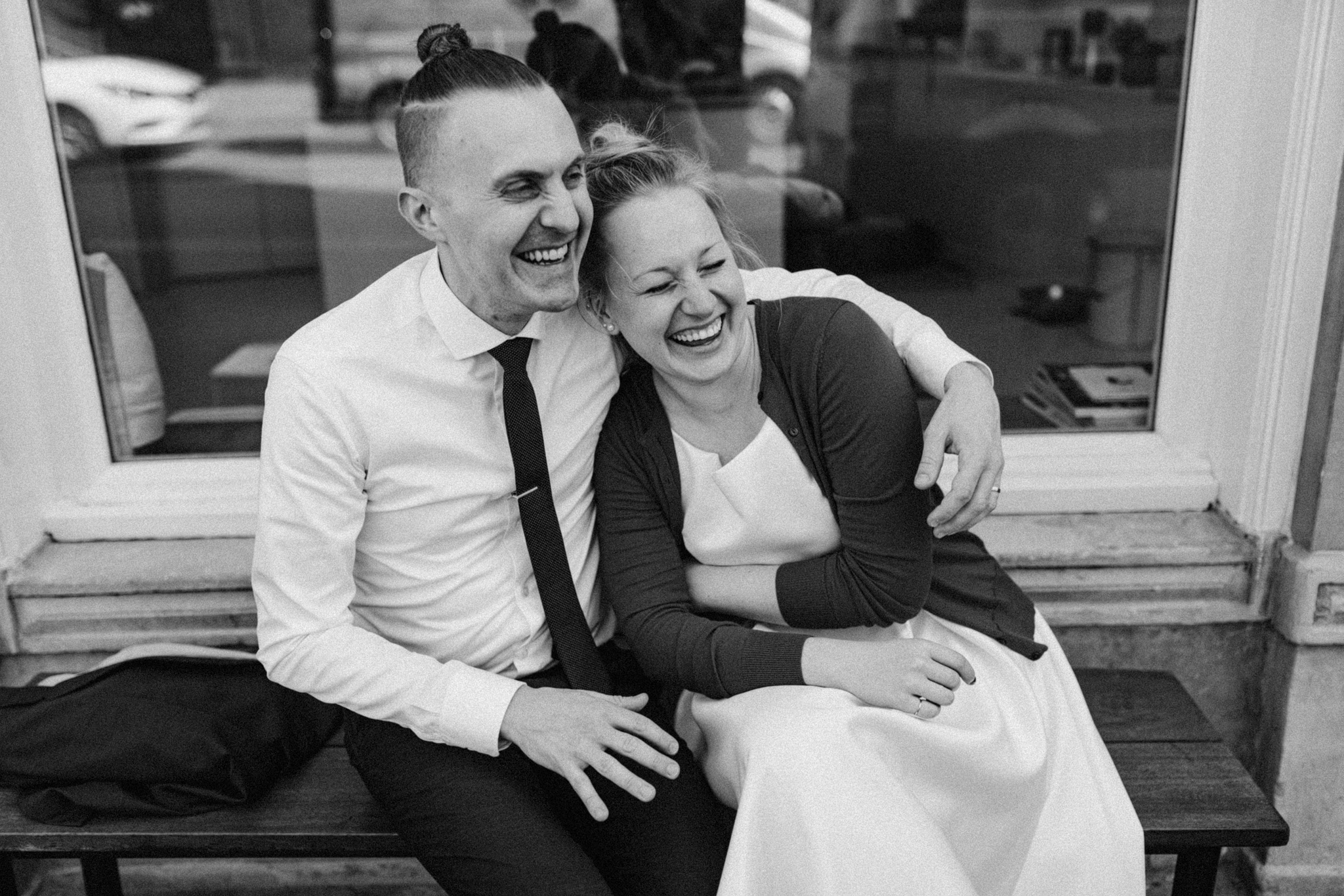 Elopement couple hugging and laughing while sitting on bench