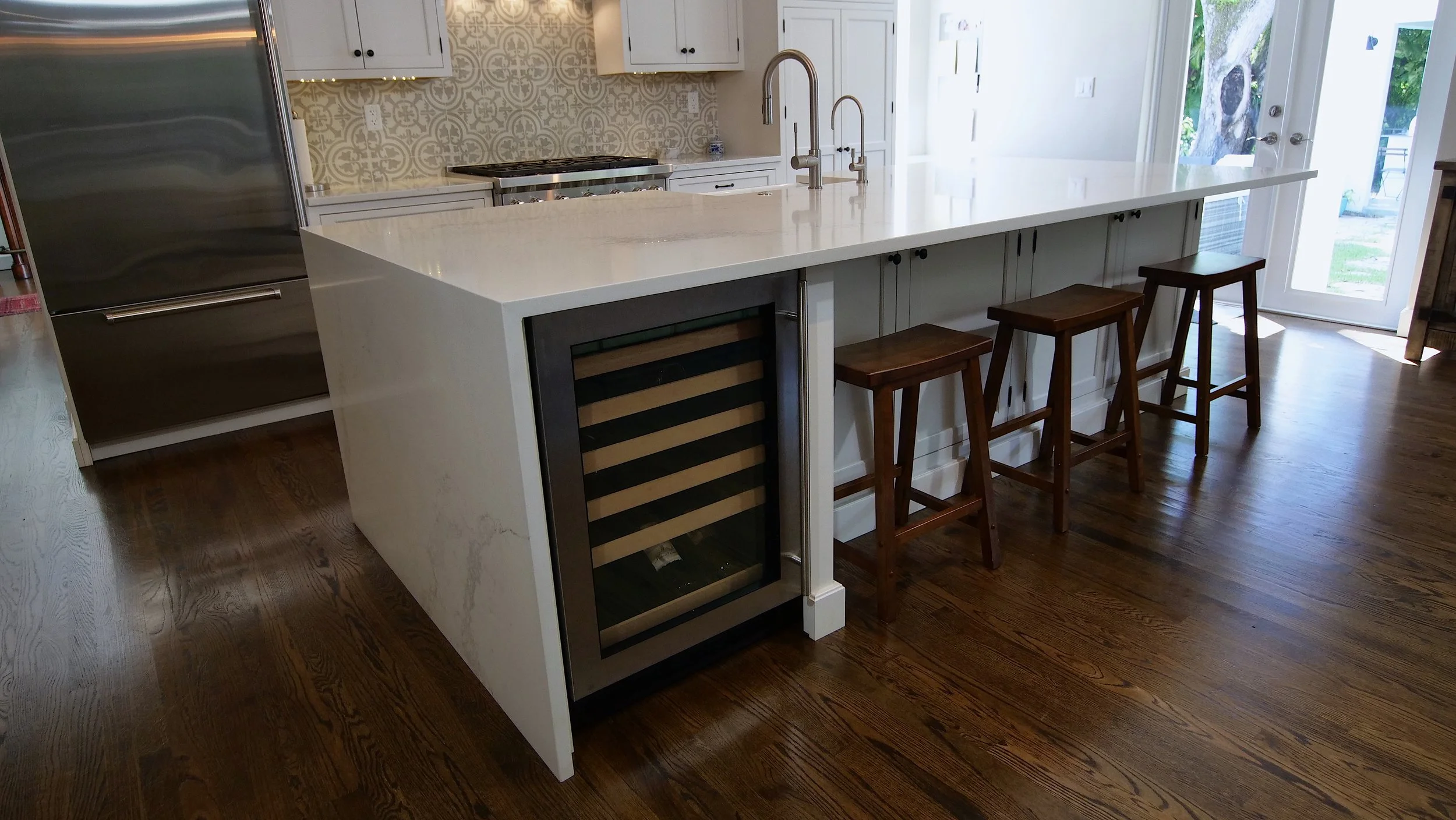 White kitchen island with built-in wine refrigerator, a sink, and wood counter stools