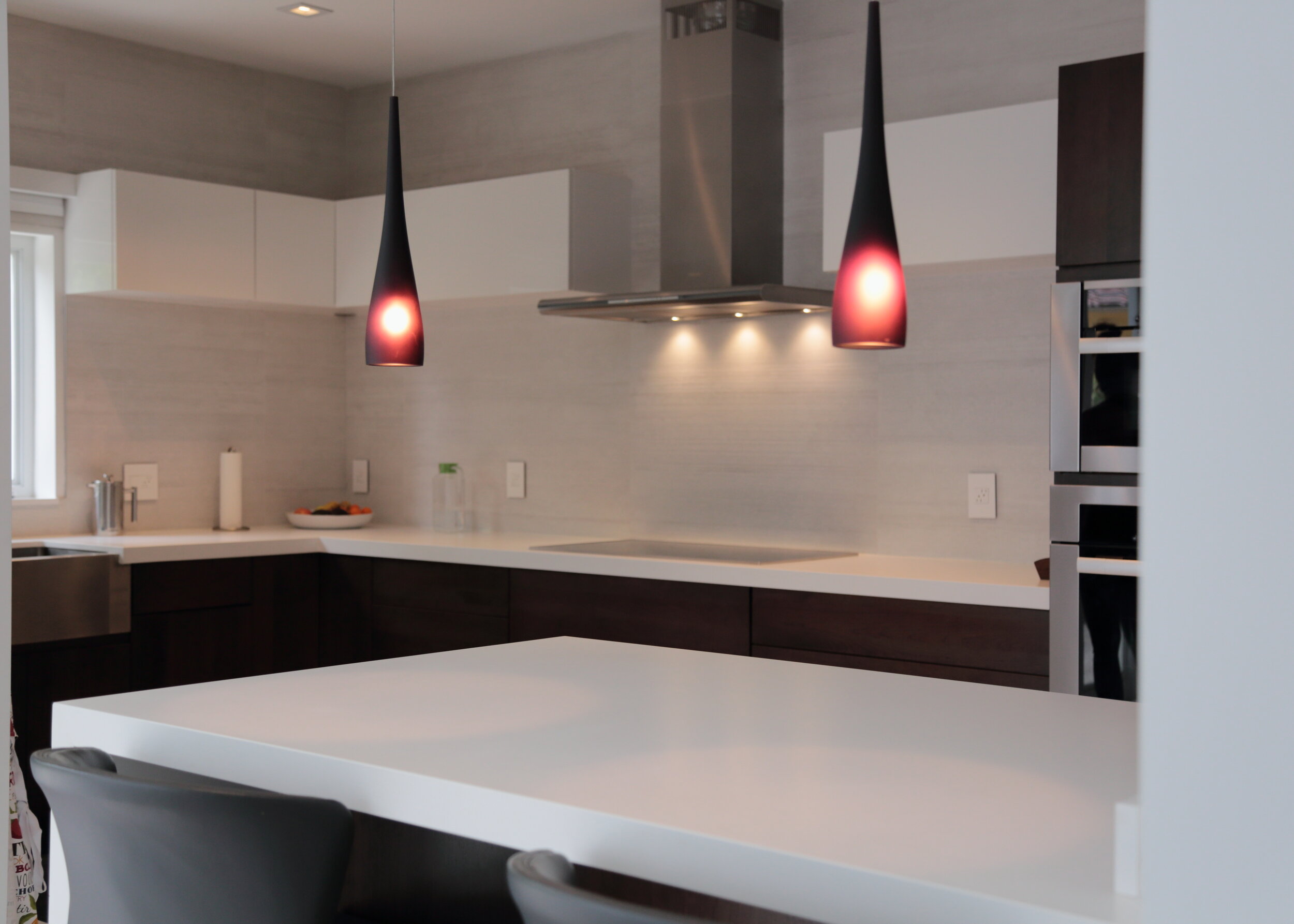 Modern Eleet galley kitchen with handle free wood cabinetry, white counters and red pendant lights