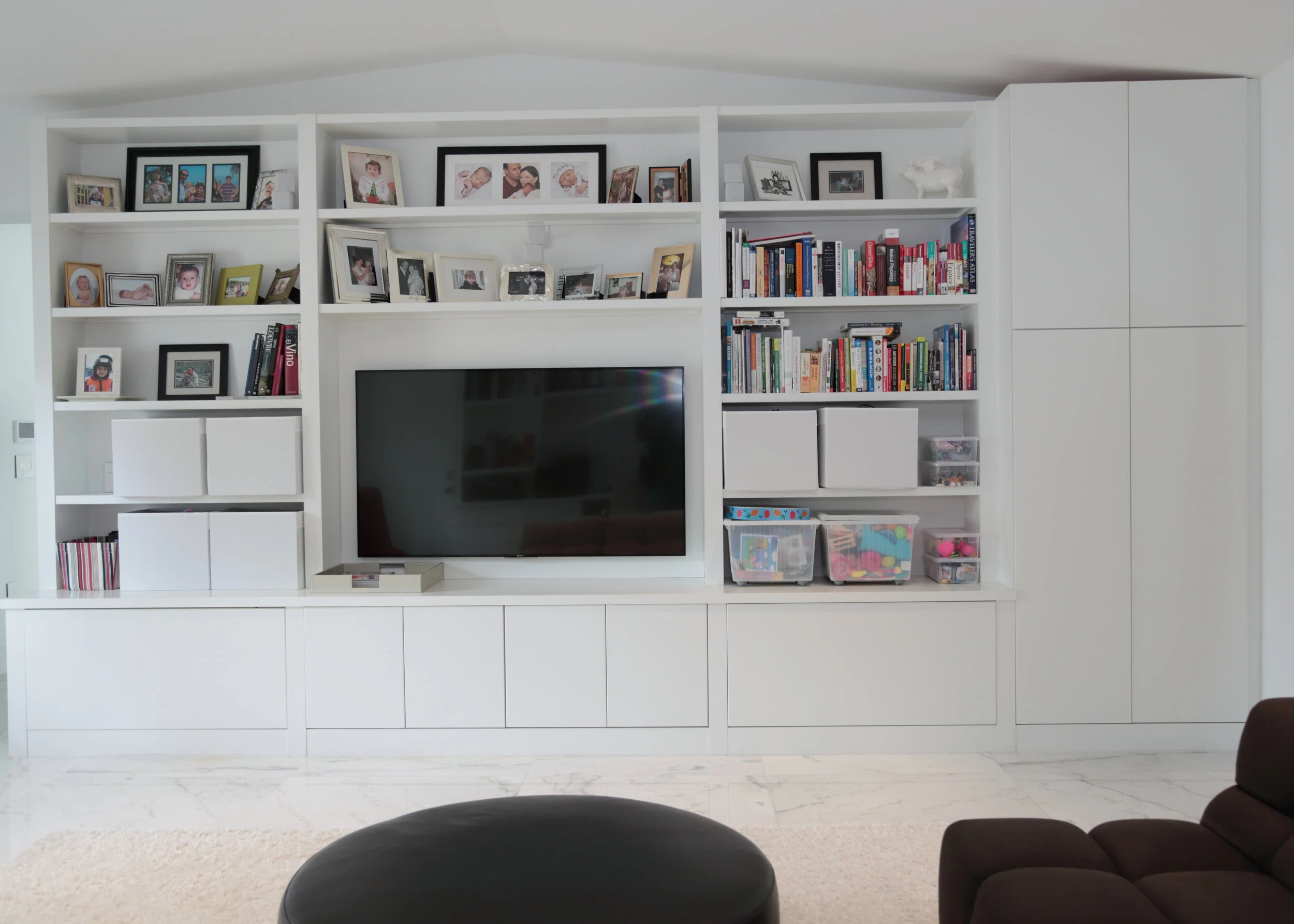 White entertainment cabinetry with open display shelves, television and concealed lower storage