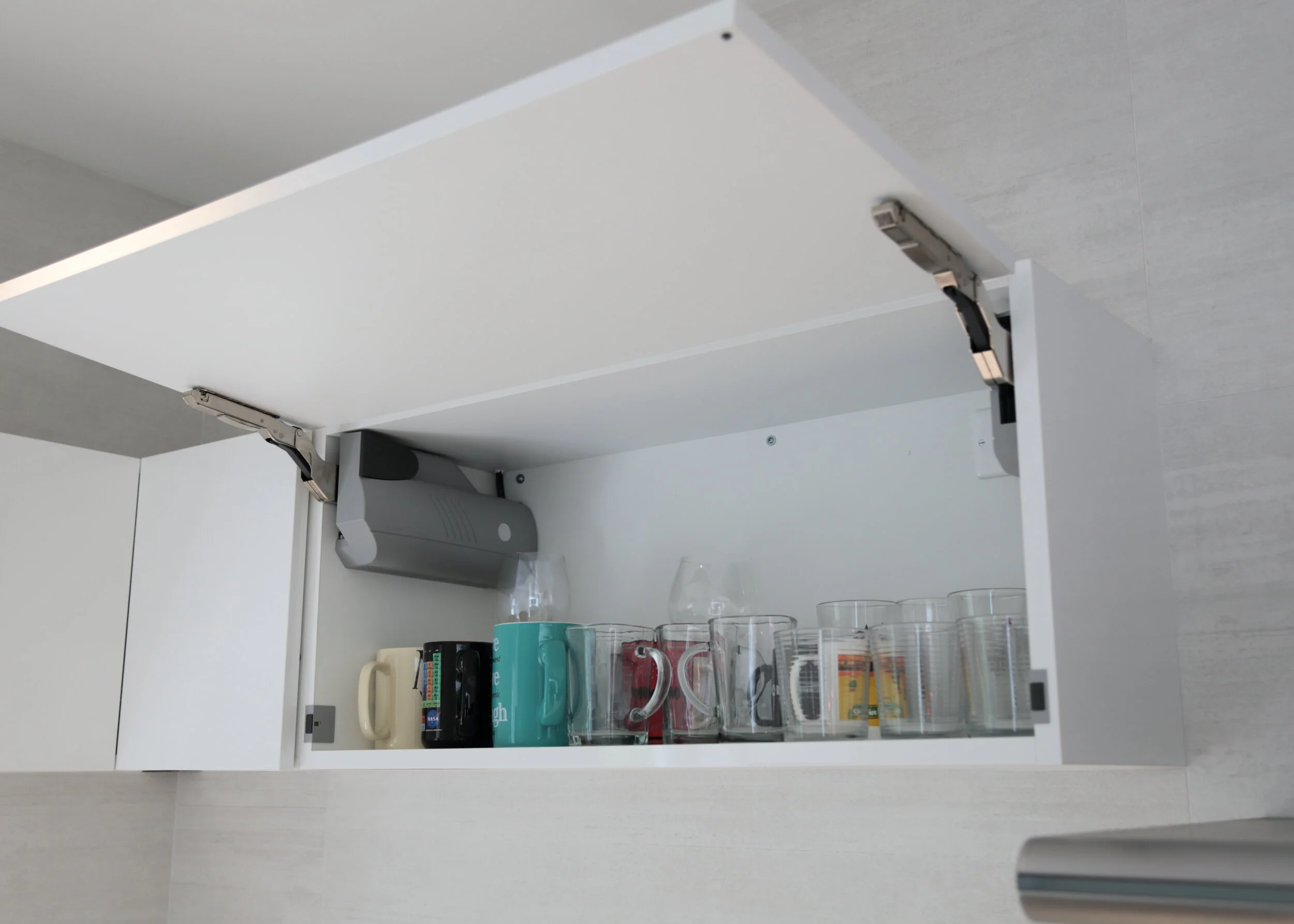 Lift up wall cabinet doors raised above the counter, revealing storage and electric opening hardware