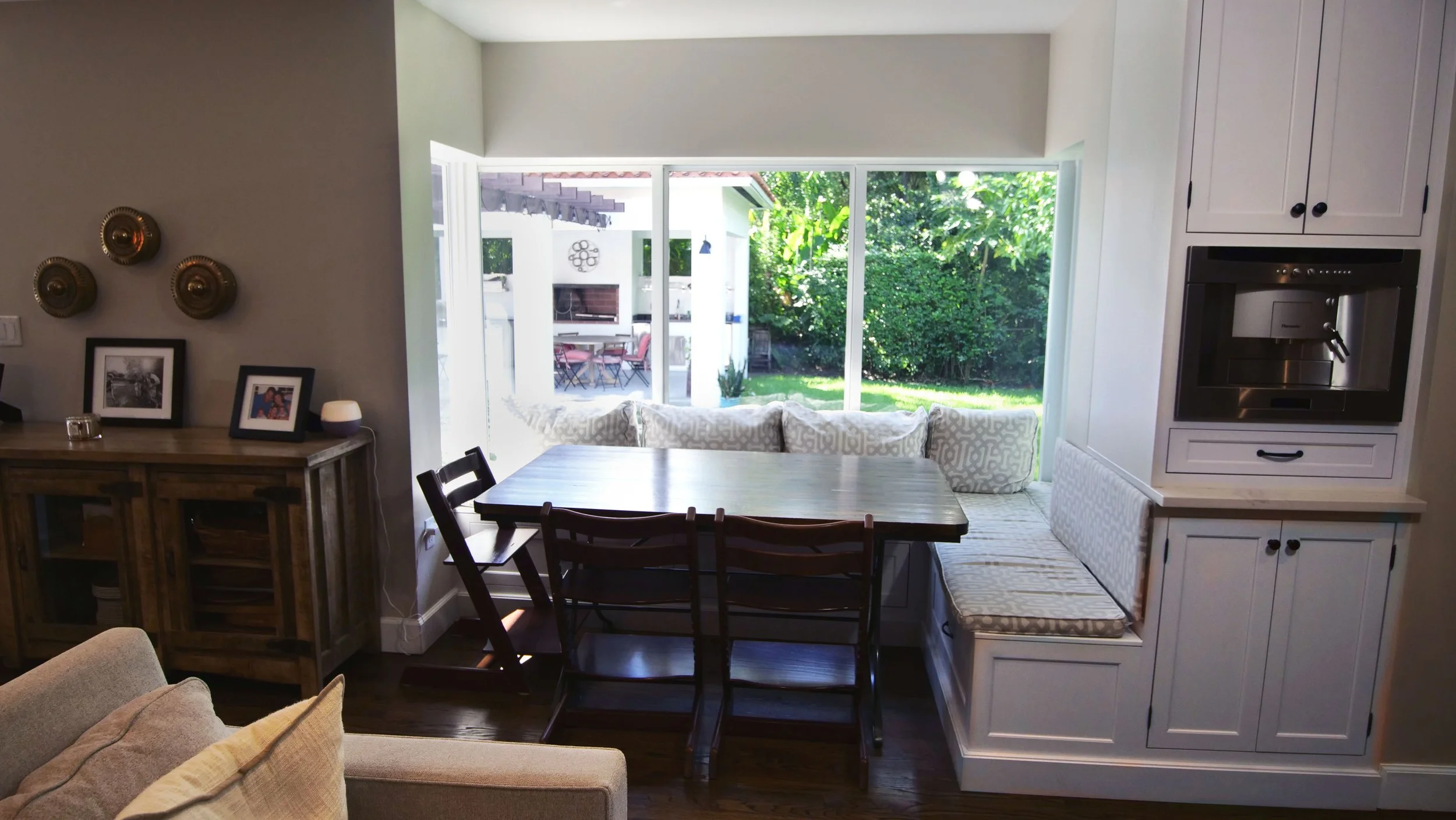 Window-side breakfast nook with a table, chairs, upholstered seating, and adjacent white coffee cabinetry