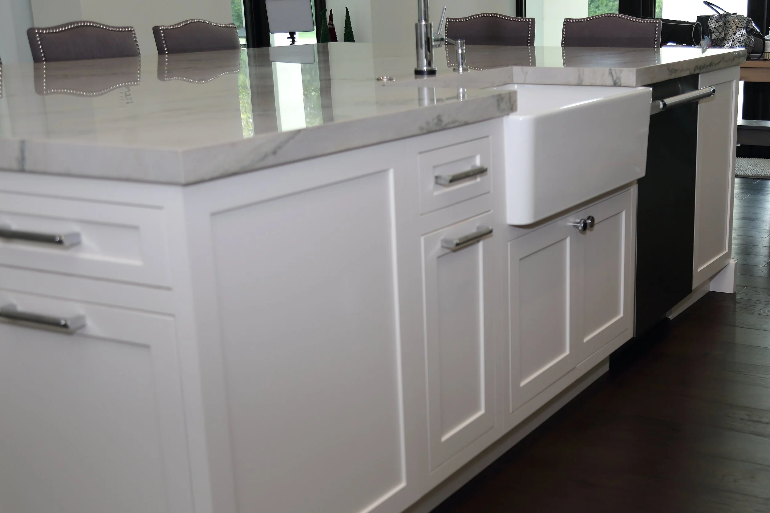 Apron-front island sink surrounded by white paneled doors and drawers