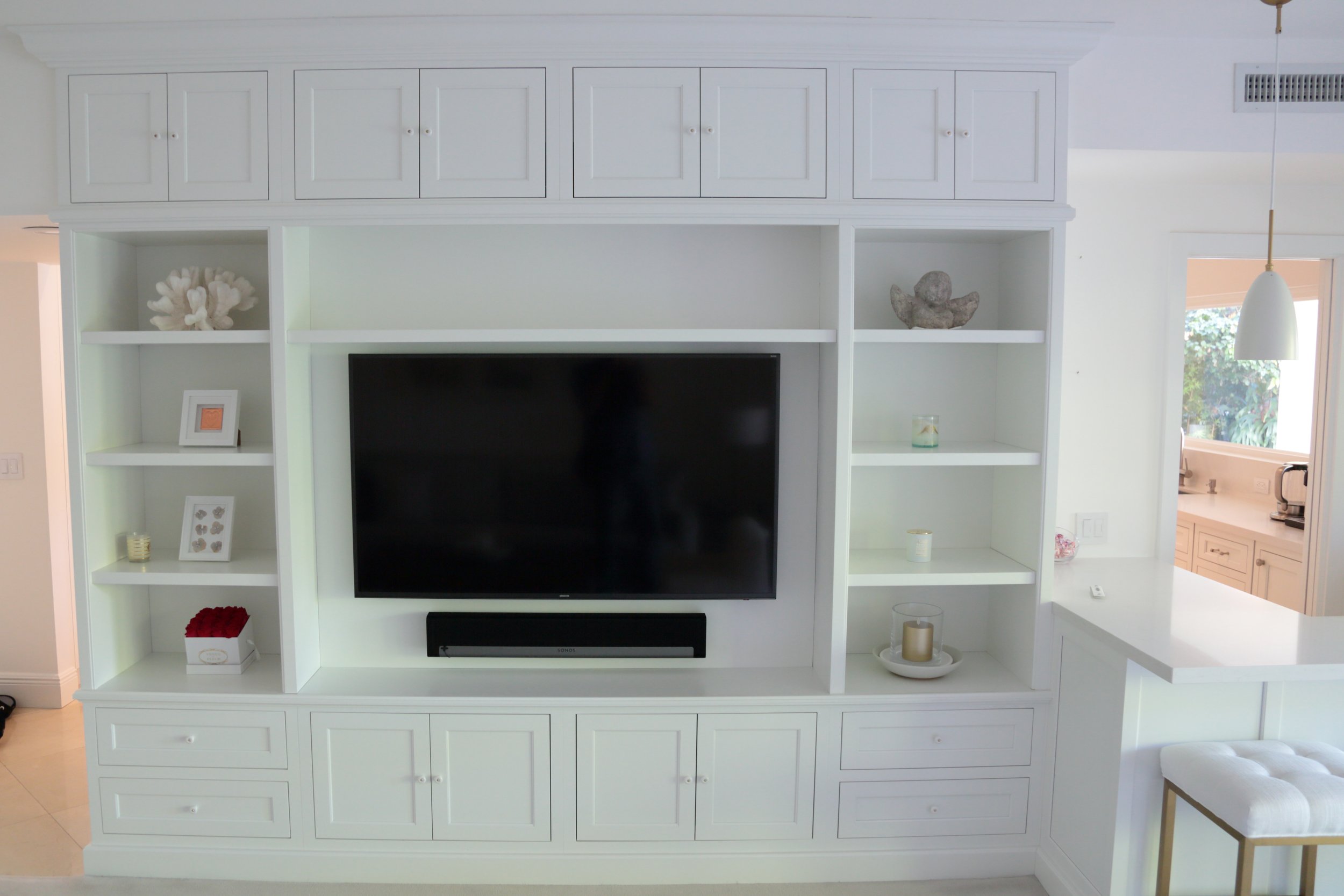 White custom entertainment built-in with television opening, open shelves, and upper and lower cabinet storage