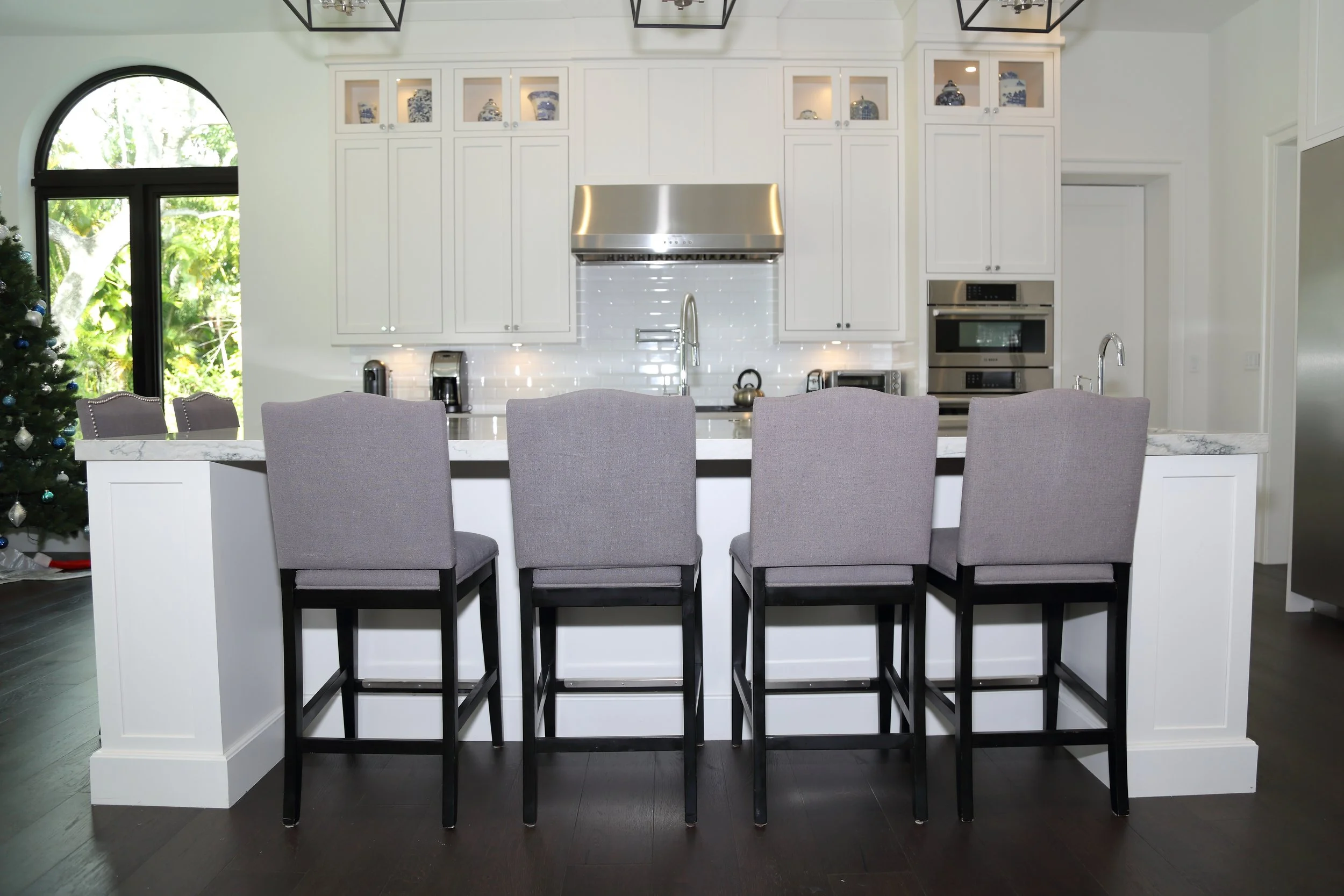 White custom kitchen island with upholstered counter stools facing the range wall