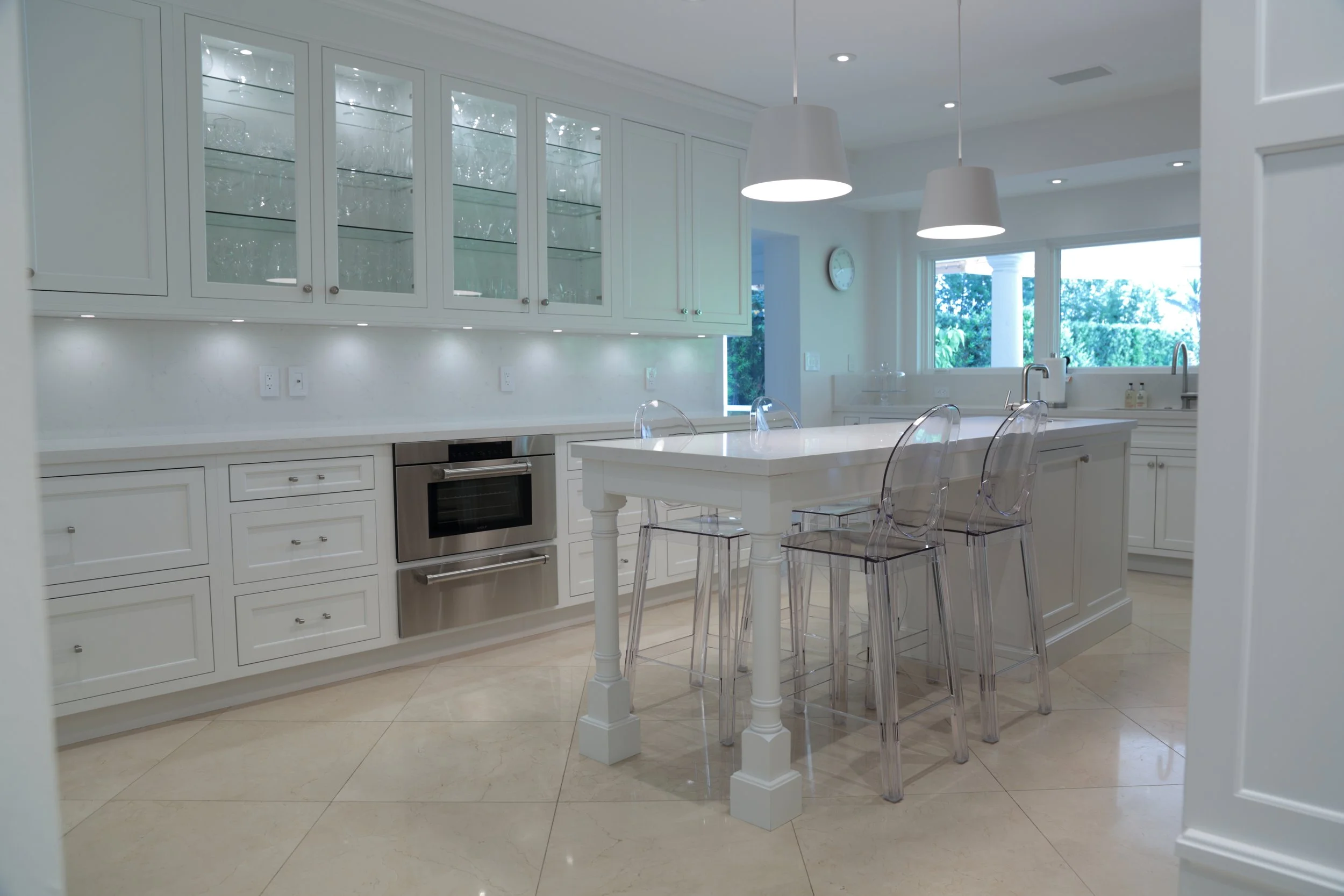 White kitchen island with counter seating alongside glass-front cabinets and drawer storage