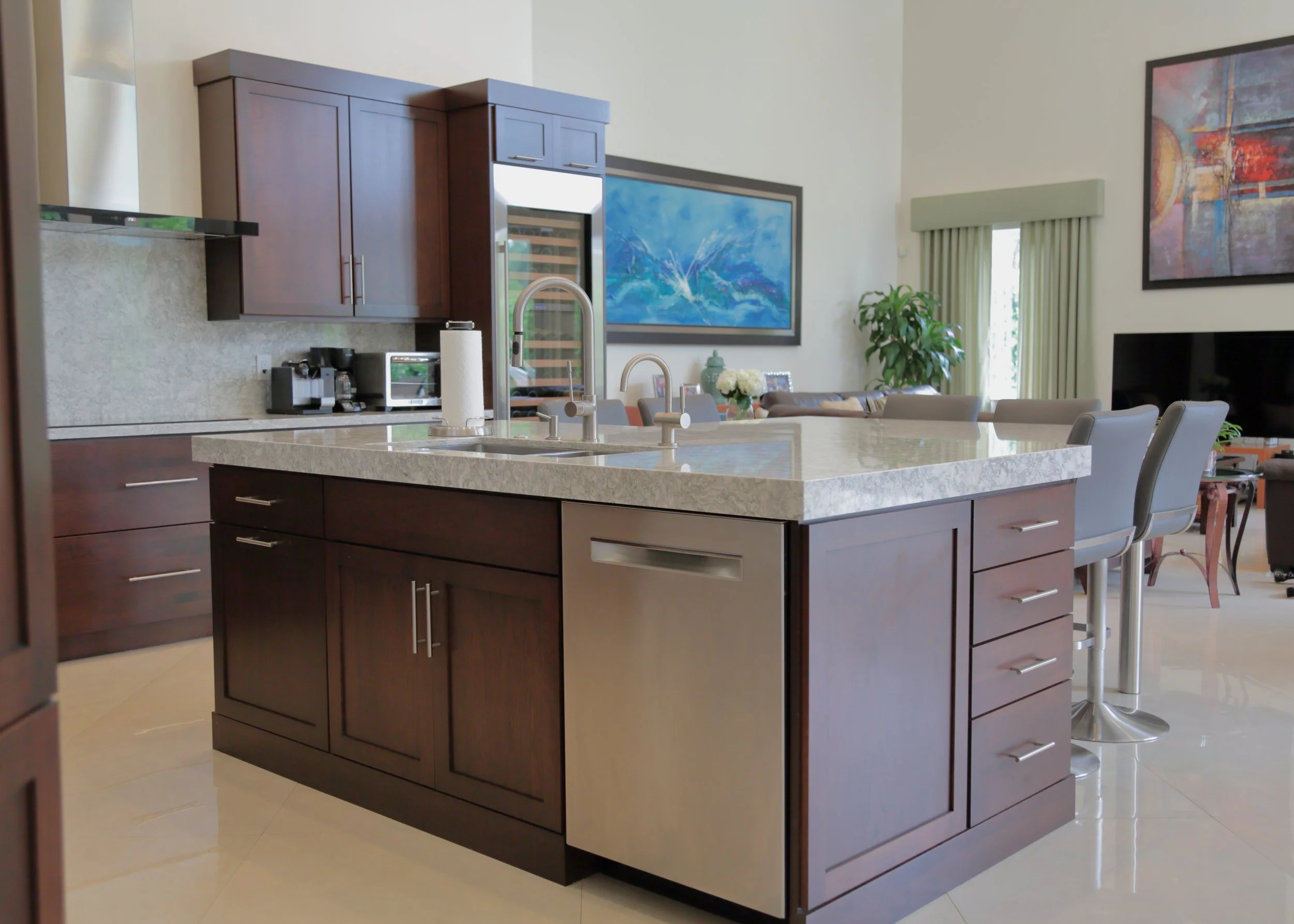 Dark wood island cabinetry with a stainless dishwasher and sink beside the main kitchen work area