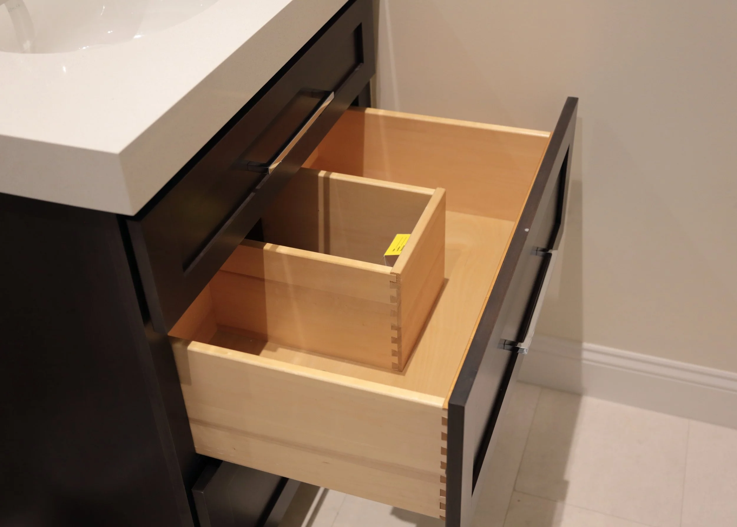 Open bathroom vanity drawer with wood dividers and storage arranged around the sink plumbing