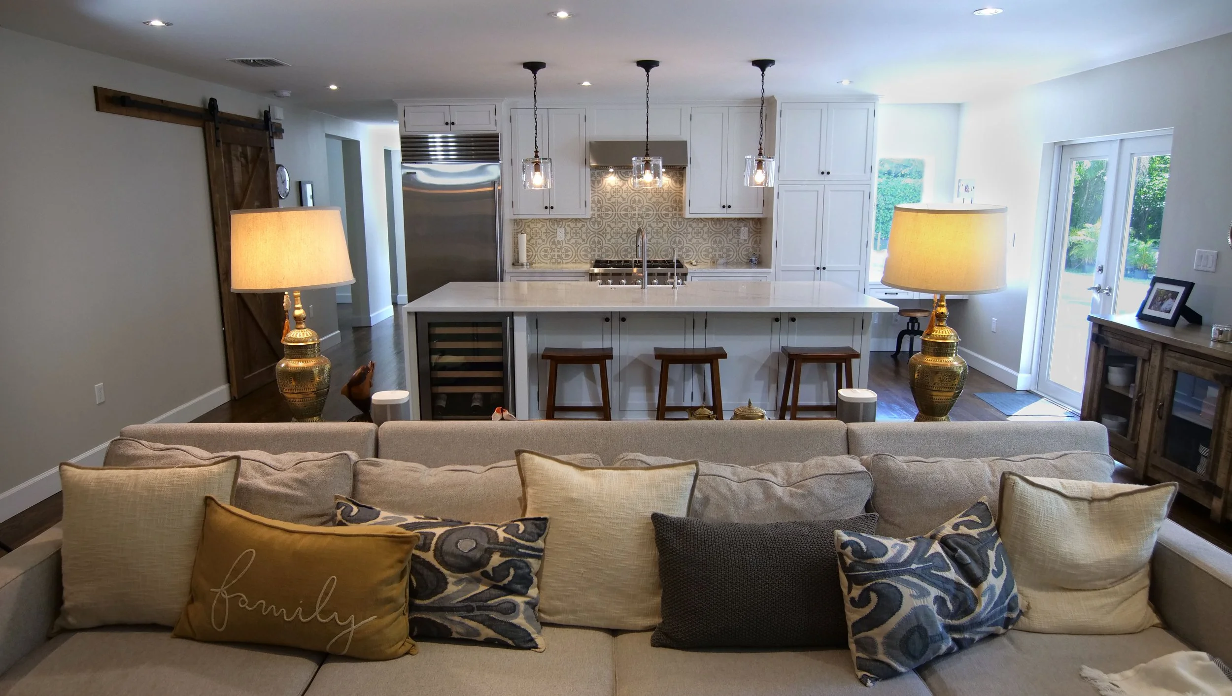 Open living room looking toward the white custom kitchen and island seating