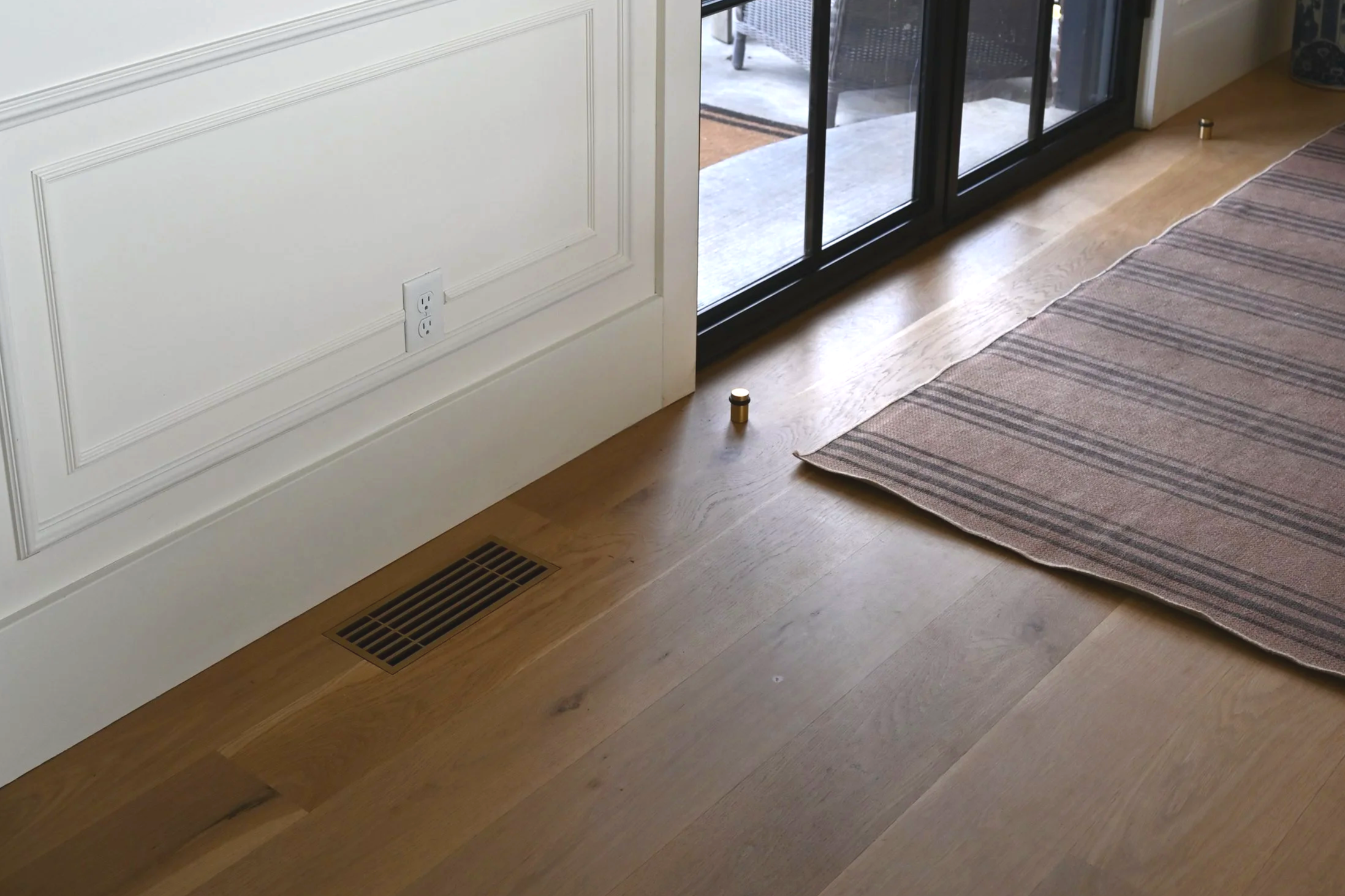 Durable flush mount decorative floor vent next to a heavy steel door. 