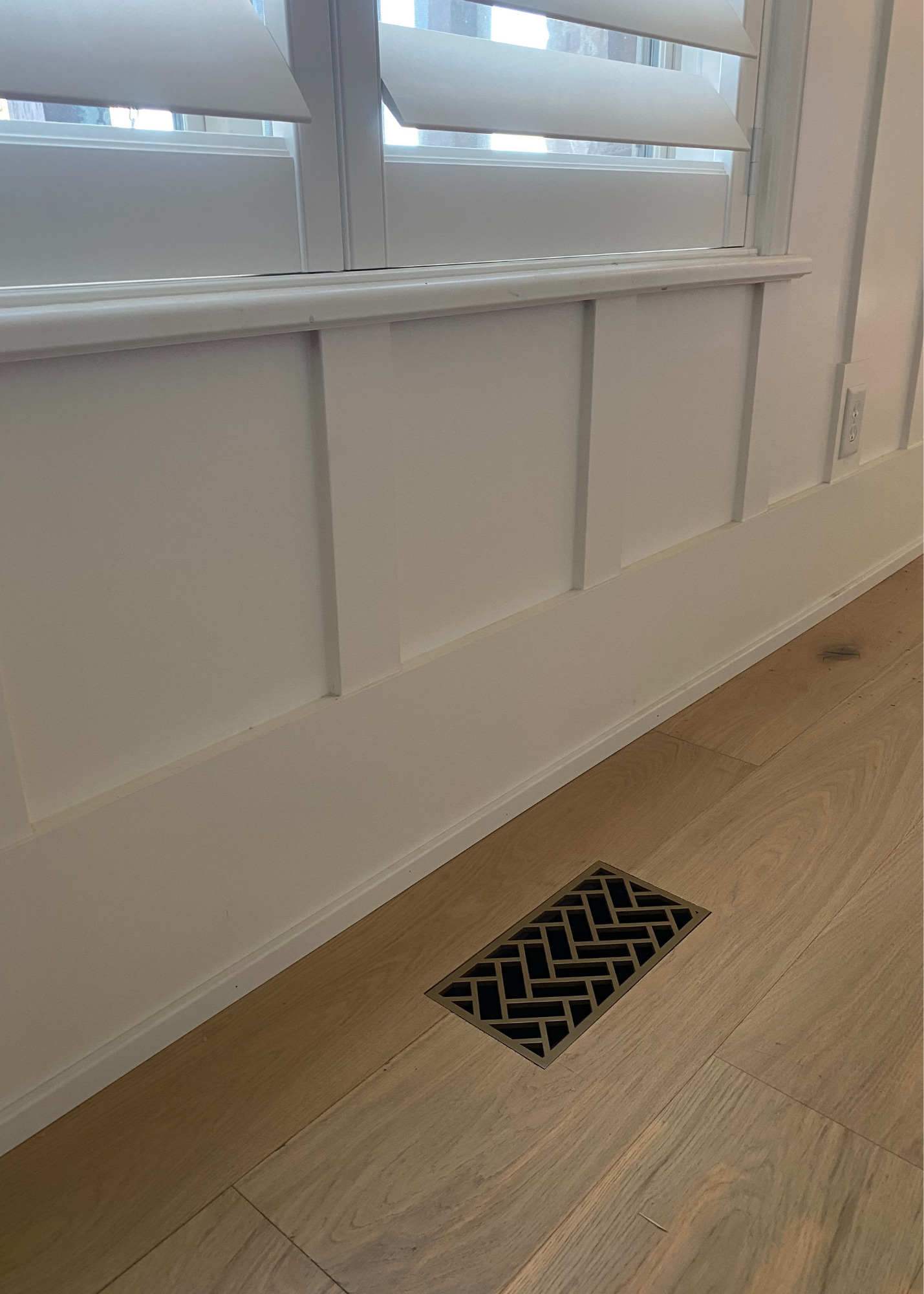 Decorative metal flush mount vent installed into a white oak floor. This is a herringbone designed steel vent that is powder coated a vintage gold. 