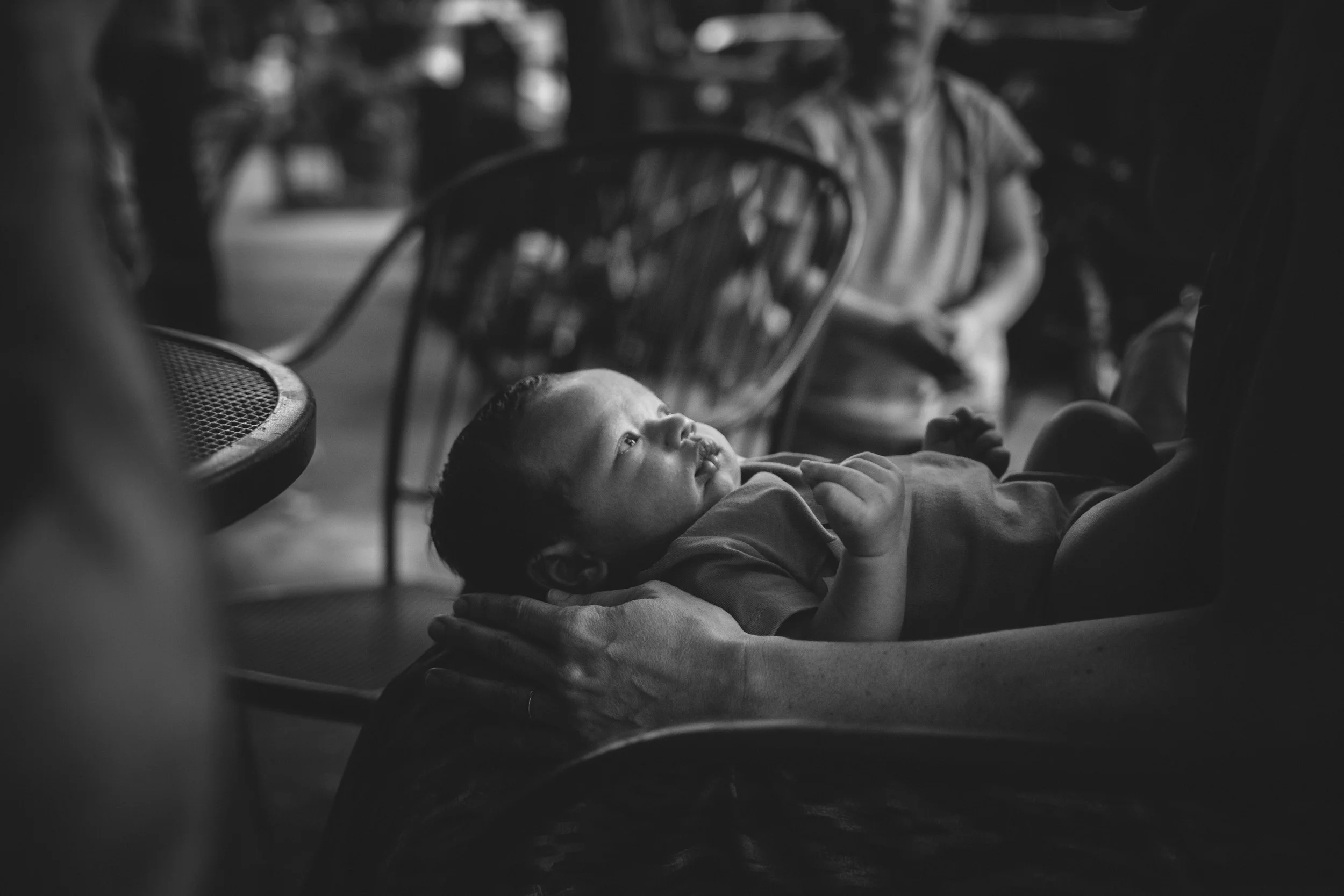 newborn baby looking up at adult from in their lap from newborn family documentary photography session in atlanta