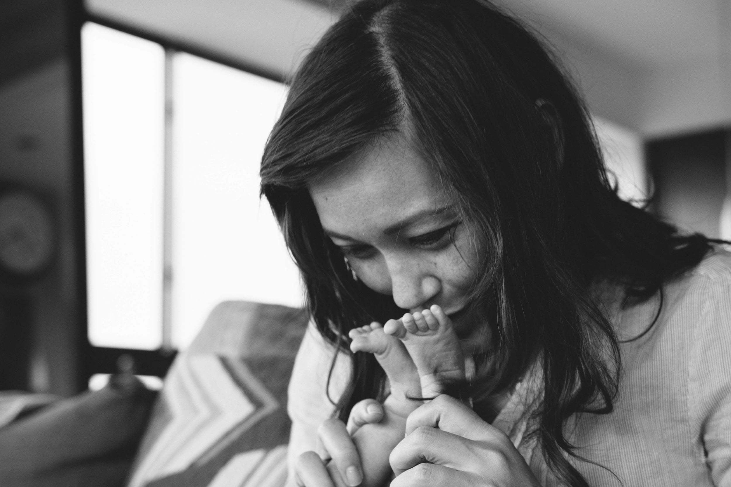 Mother kisses baby's toes from newborn family documentary photography session in atlanta