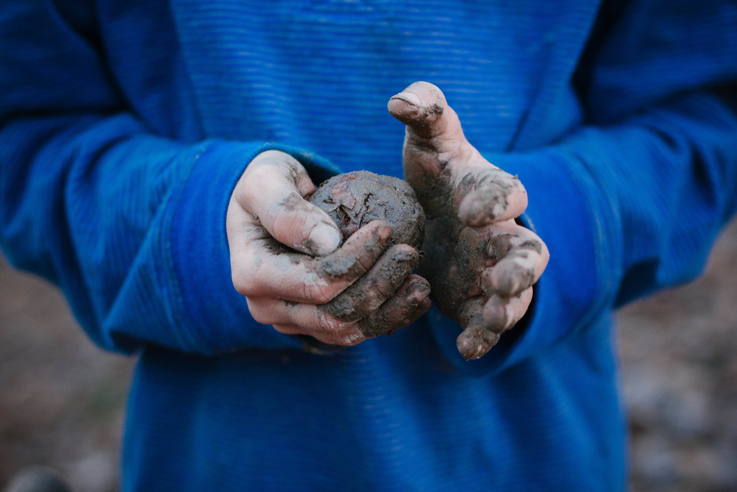 boy making a mud ball with his hands from a portrait of play documentary photography session in atlanta