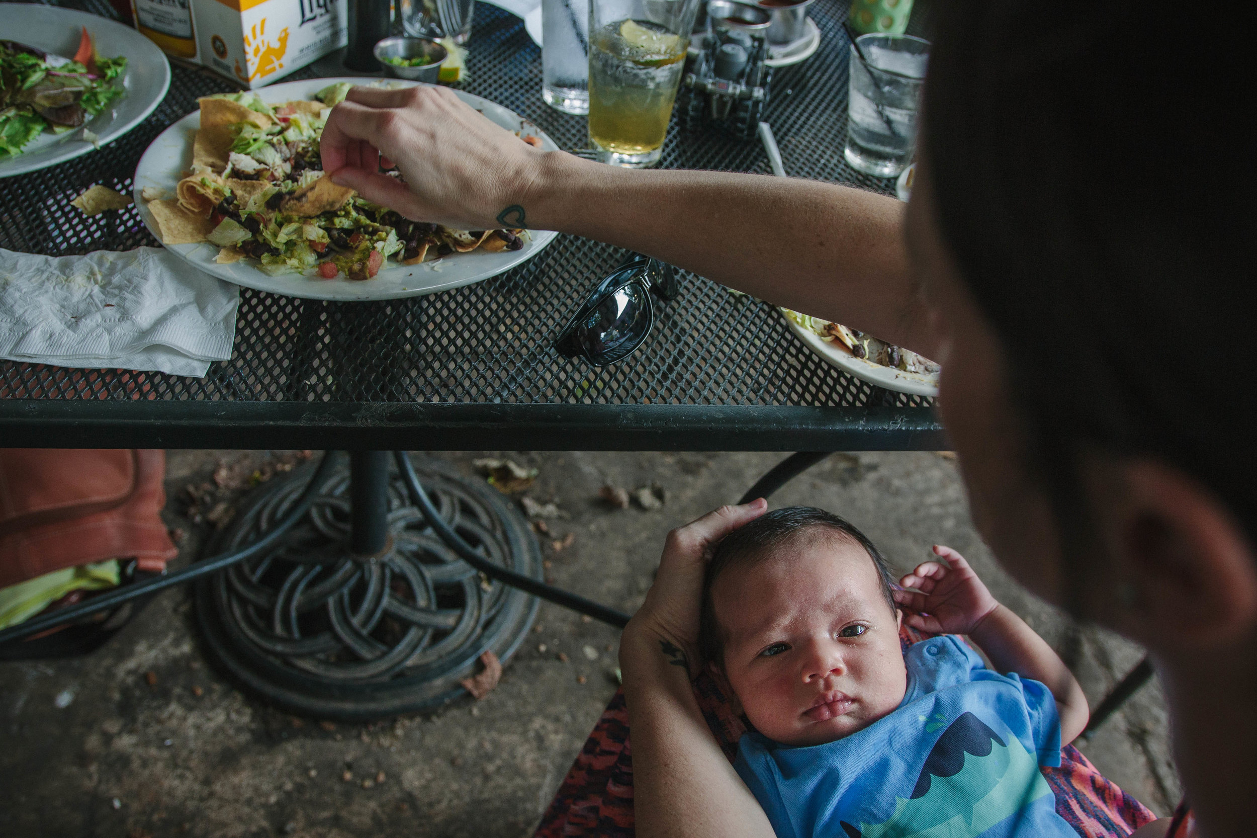 Mother holding newborn and reaching for a chip from a newborn family documentary photography session in atlanta