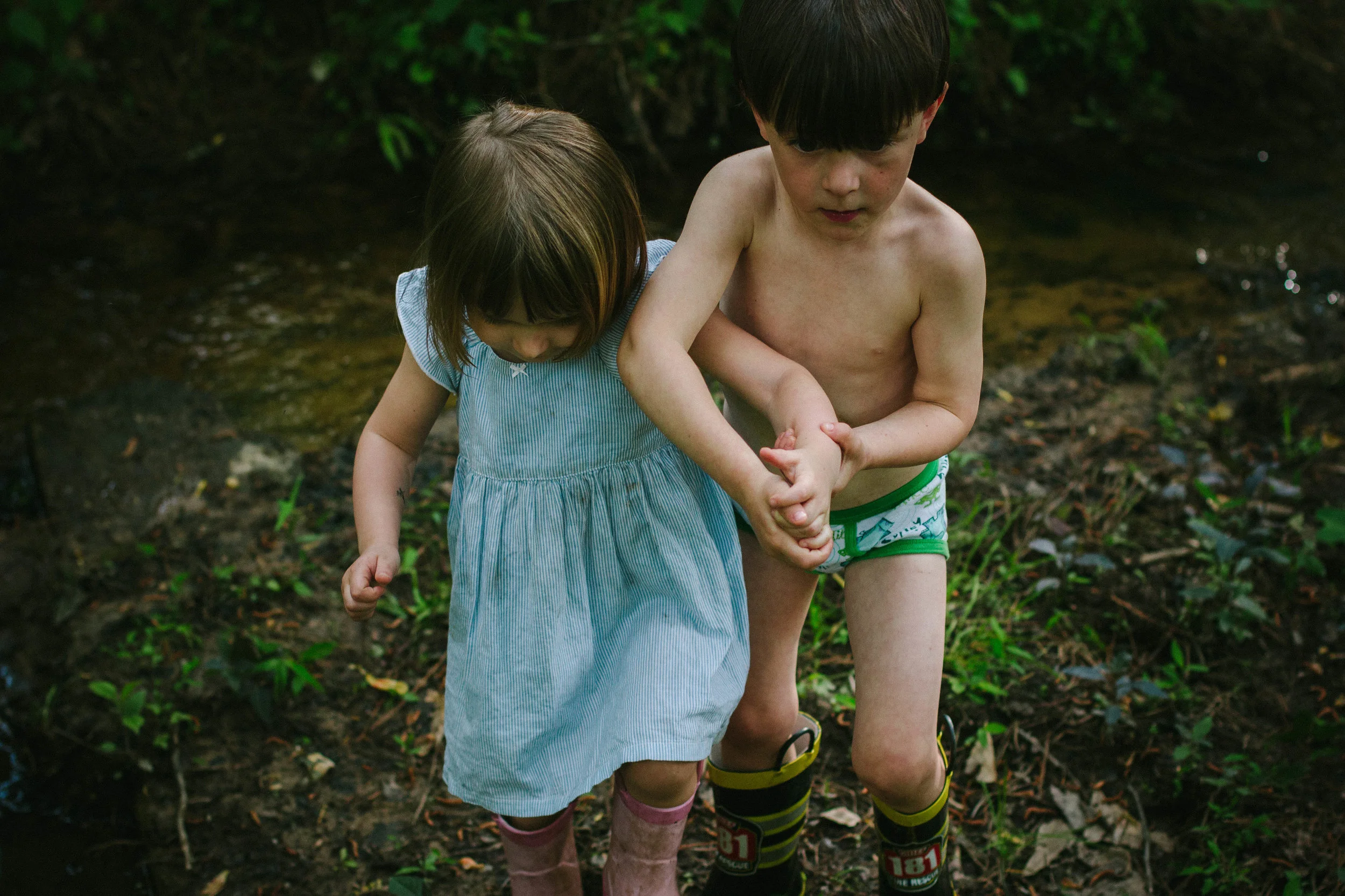 Girl and boy holding hands while crossing a creek from portrait of play documentary photography session in atlanta