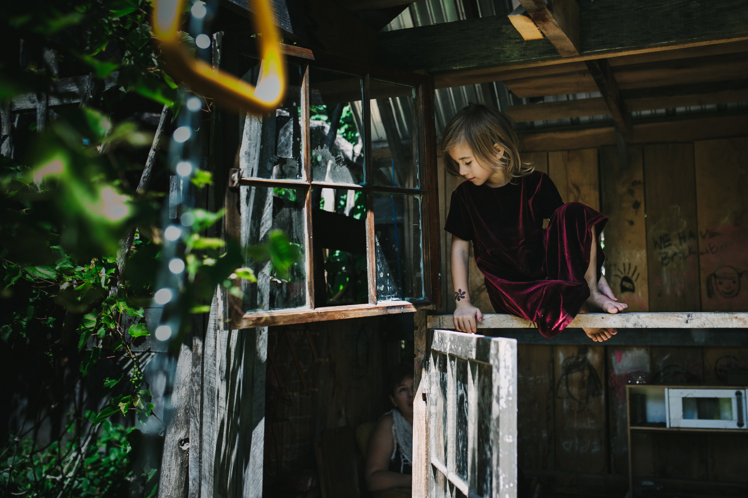 Girl in a playhouse looking down from portrait of play documentary photography session