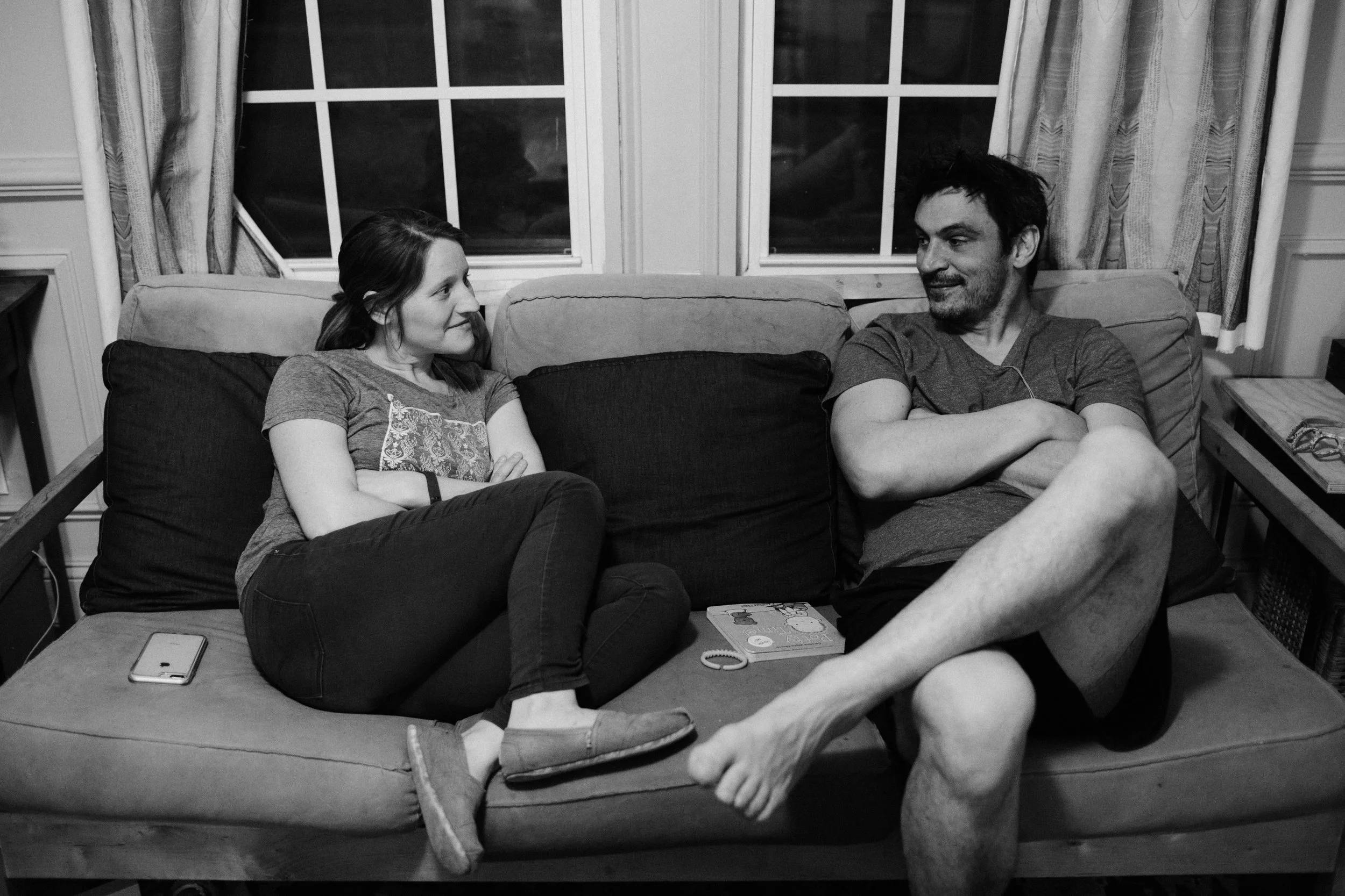 a couple sits on the couch and looks at each other